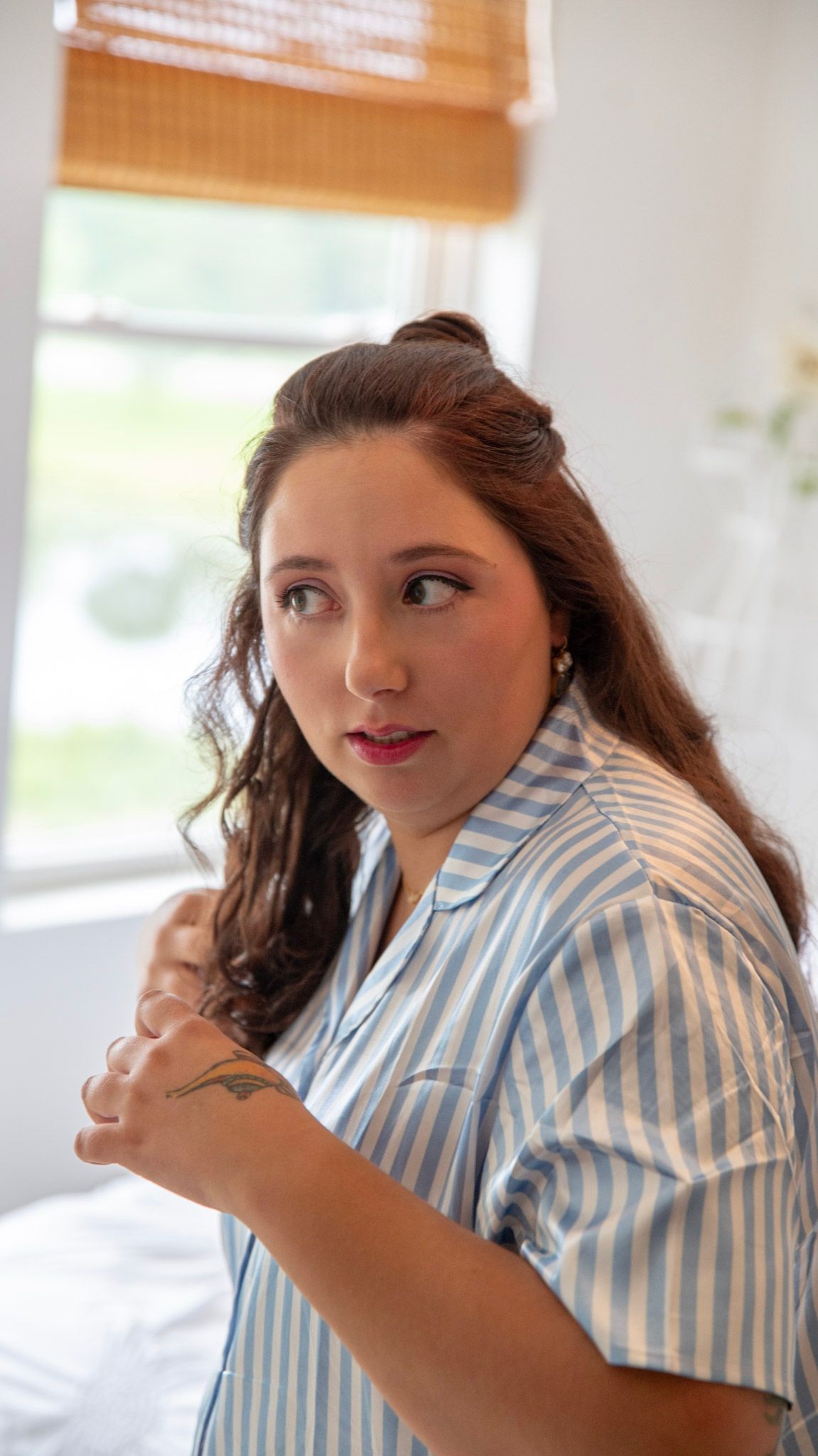 Person in striped shirt making playful expressions in a bright indoor setting.