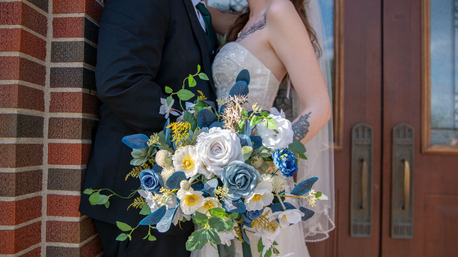 Wedding party members embrace and celebrate outside a brick church.