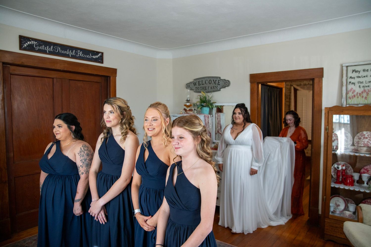 Wedding party in navy blue dresses gathered in bright indoor room.