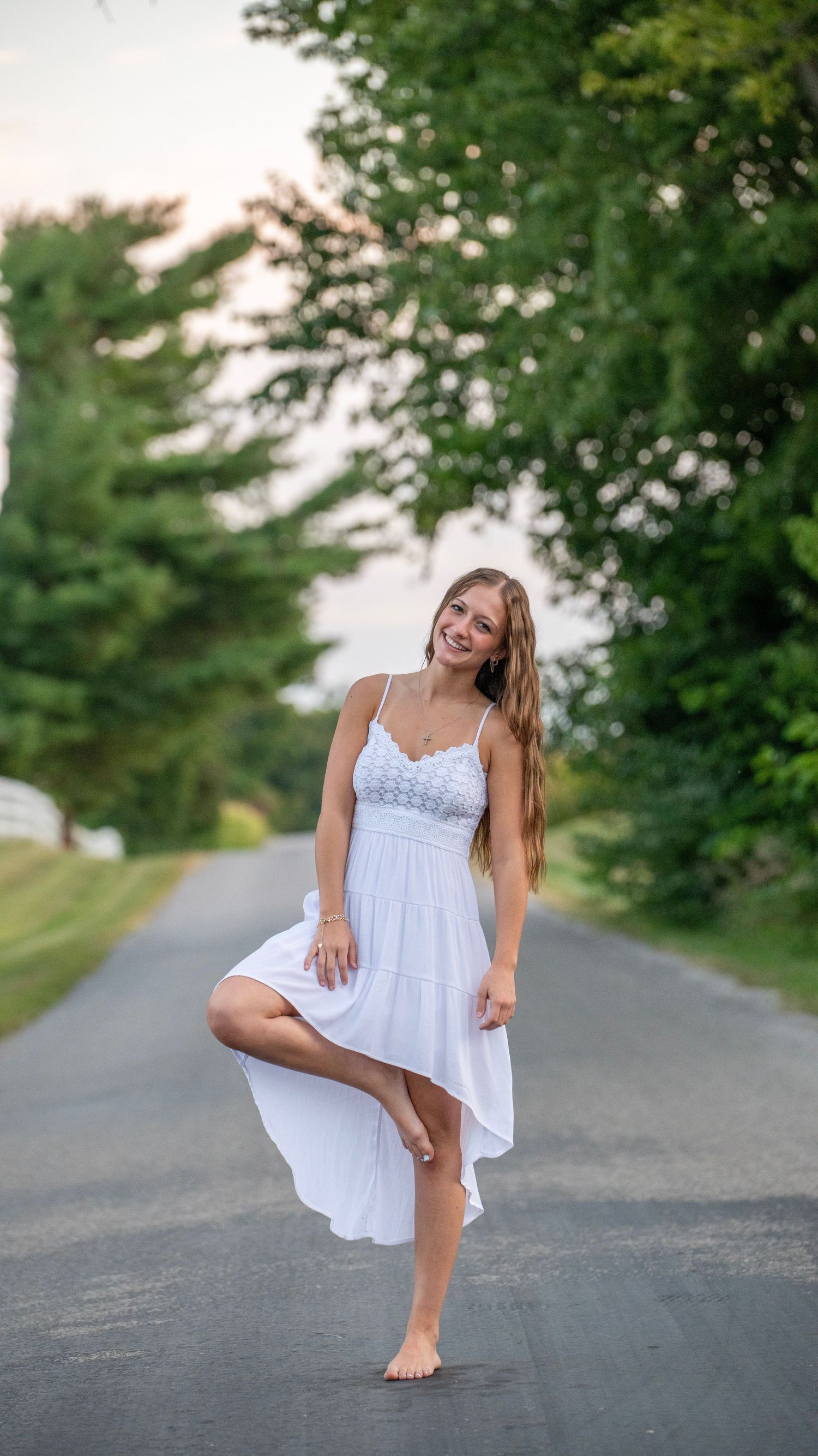 Playful dance poses on a country road in a white summer dress.
