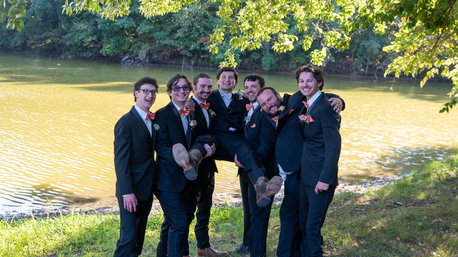 Wedding party poses for group photos in a scenic outdoor garden setting.