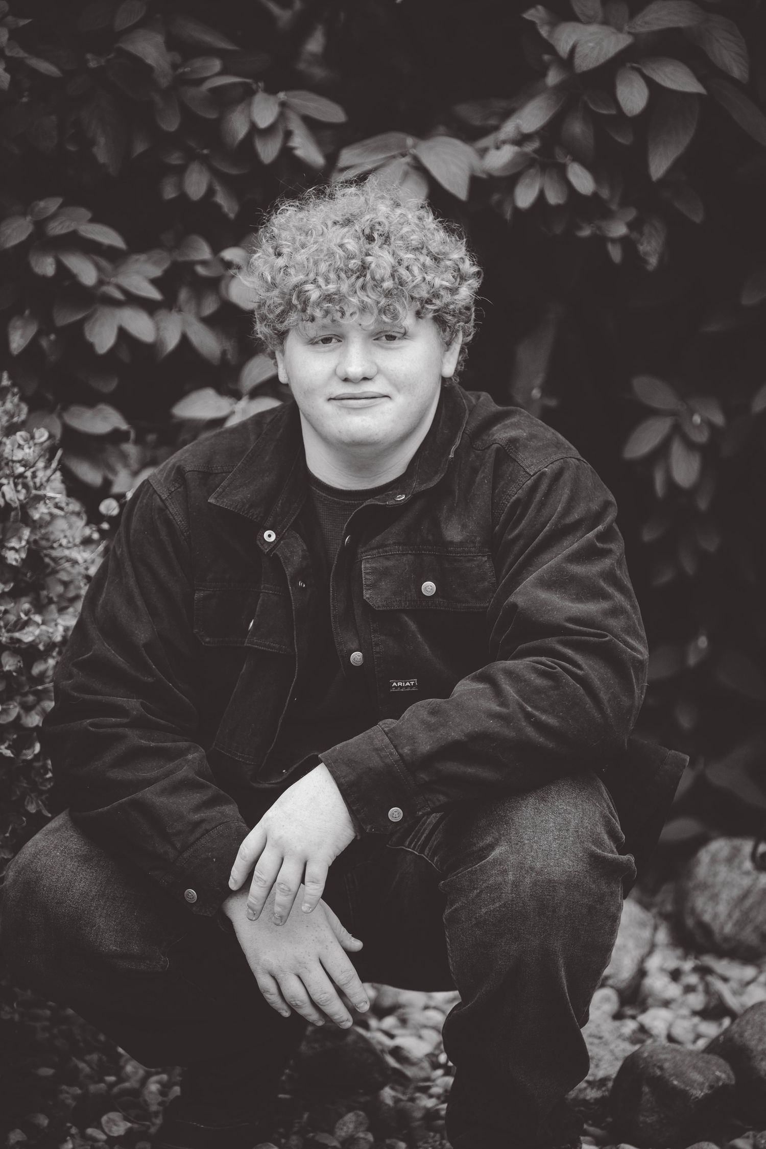 Black and white portrait series with foliage background showing casual outdoor poses.