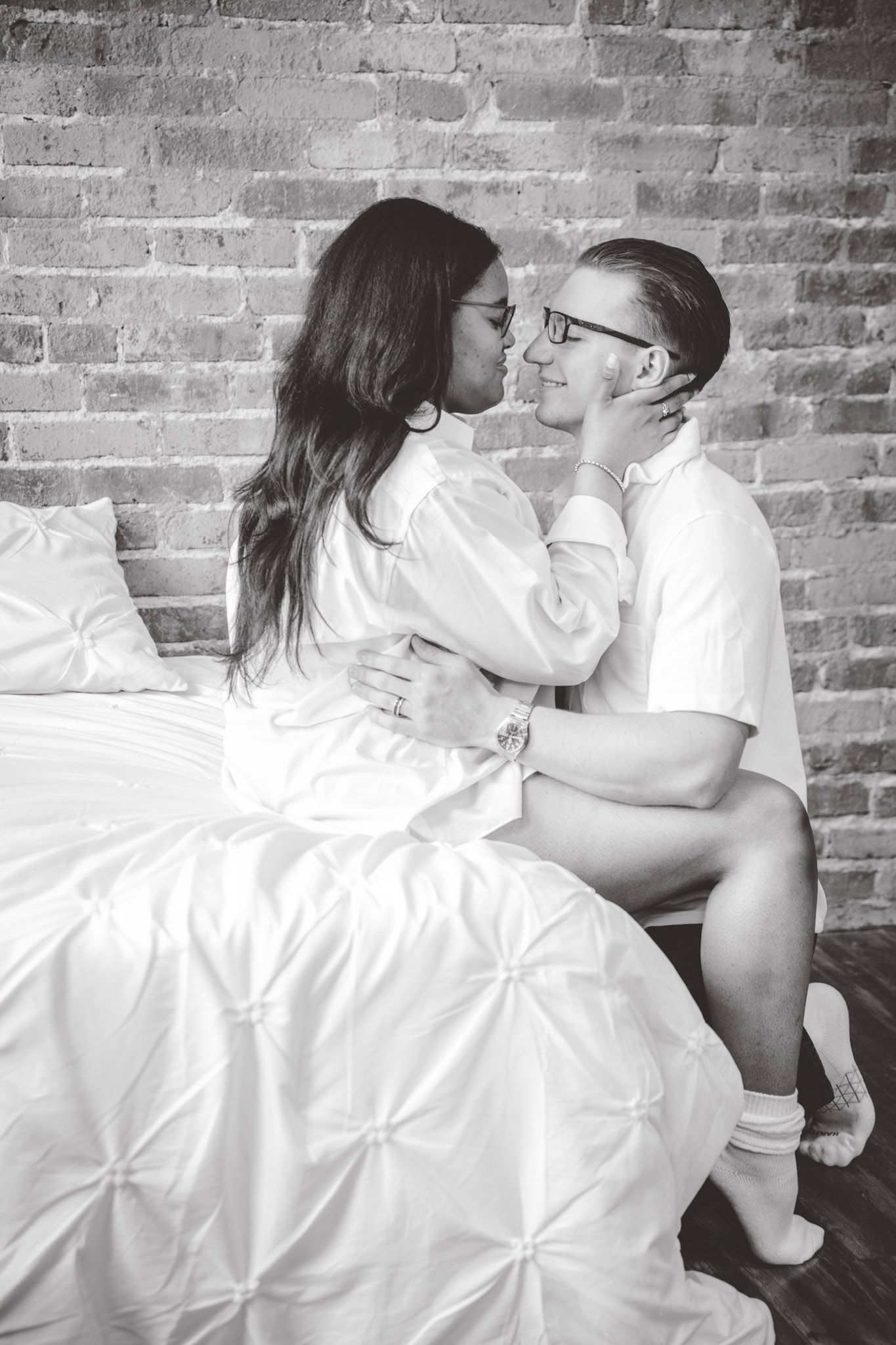 Black and white romantic portraits against textured brick wall with white fabric details.