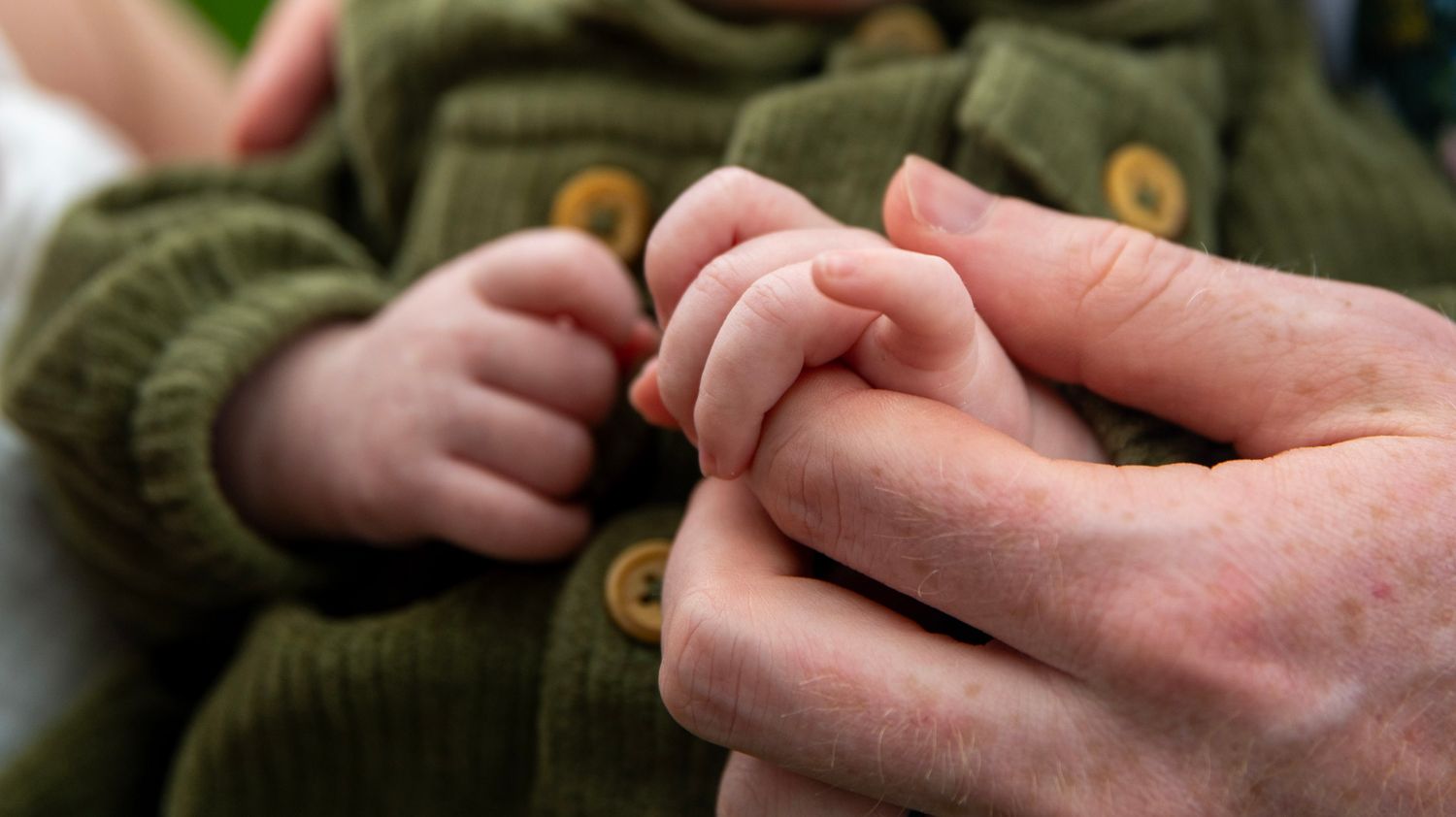 Close-up detail of hands gently holding and caressing in black and white.