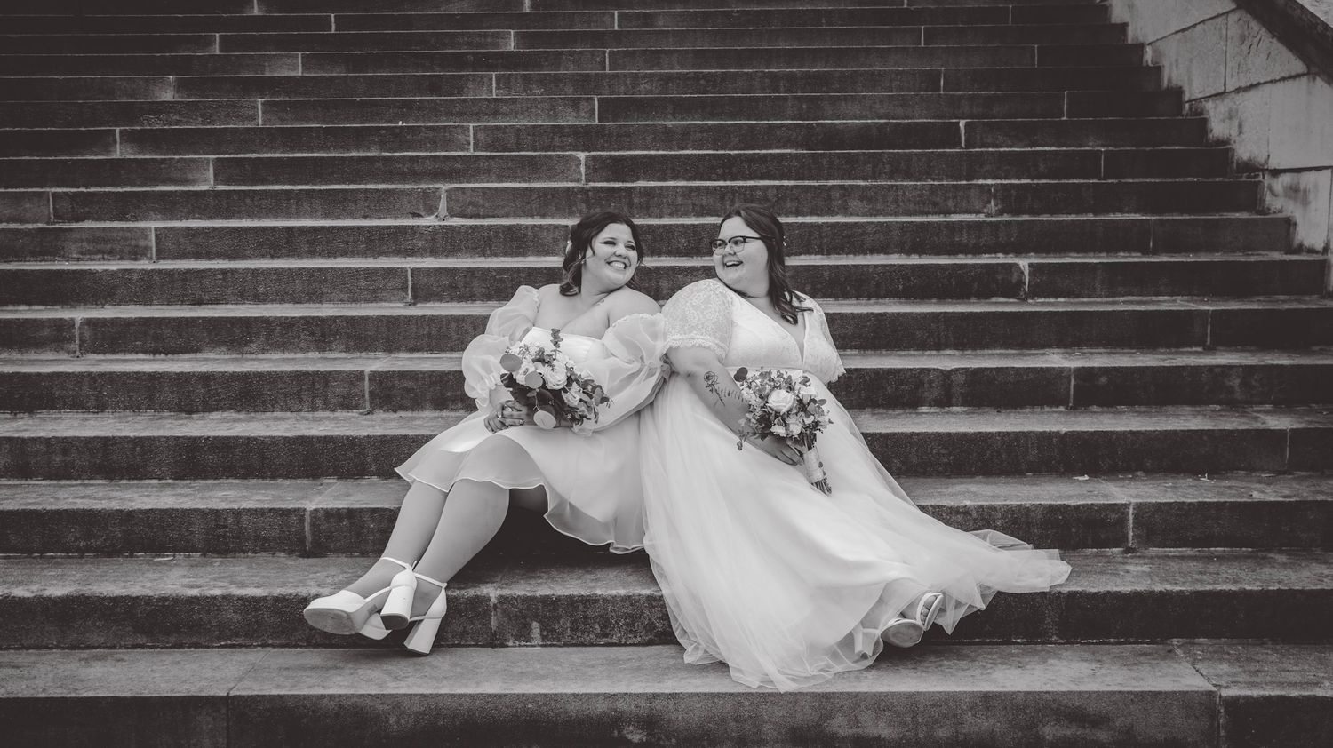 Black and white photo of couple posing on stone steps.