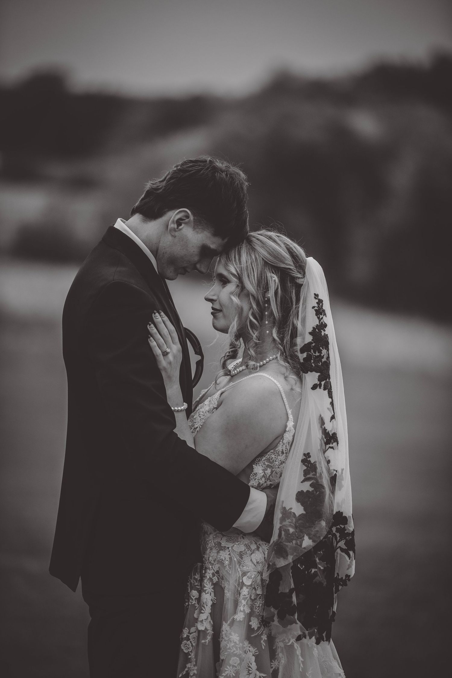 Black and white wedding portrait showing emotional connection between newlyweds.