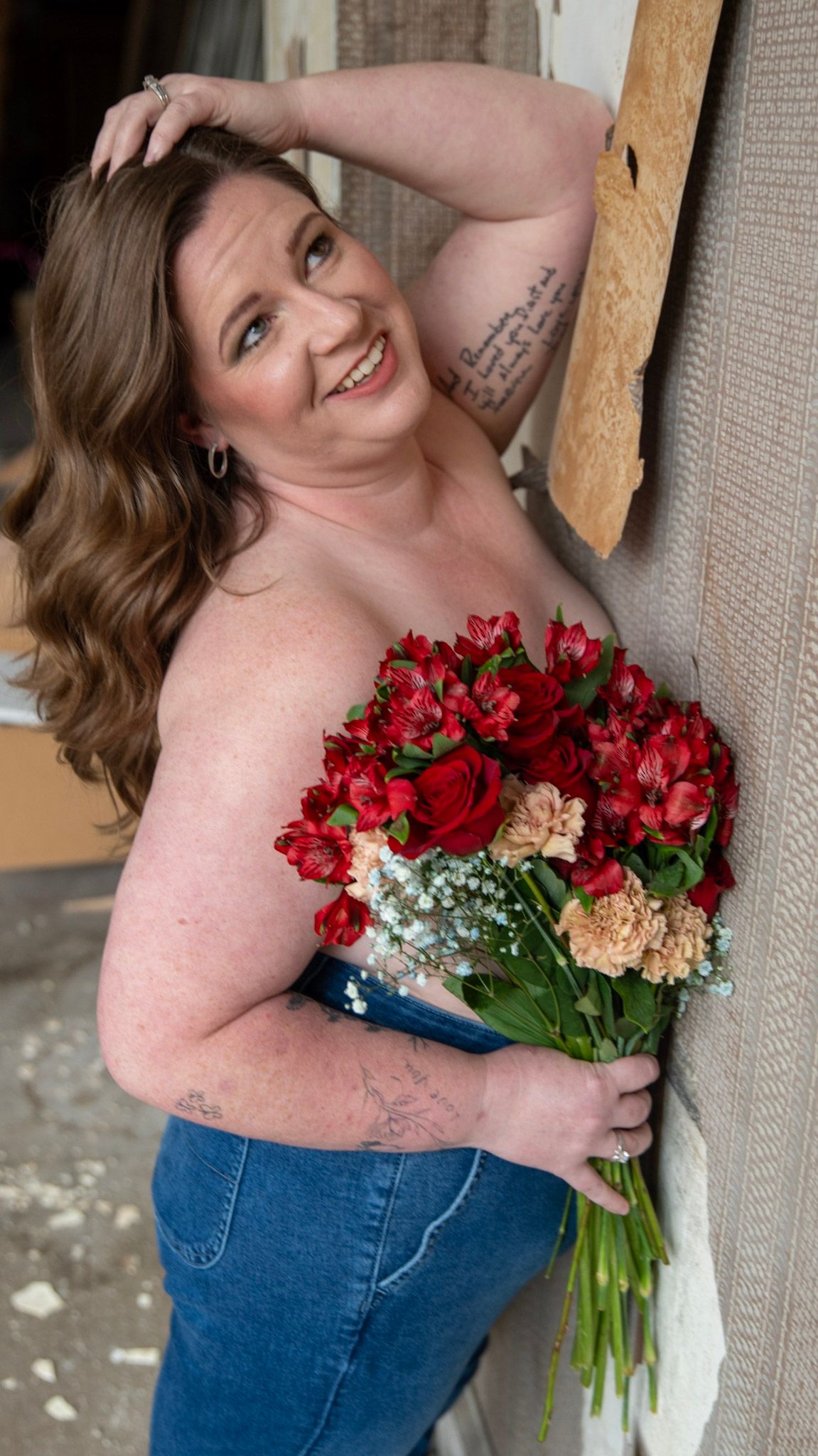 Cropped portrait highlighting floral arrangement of red roses and greenery.