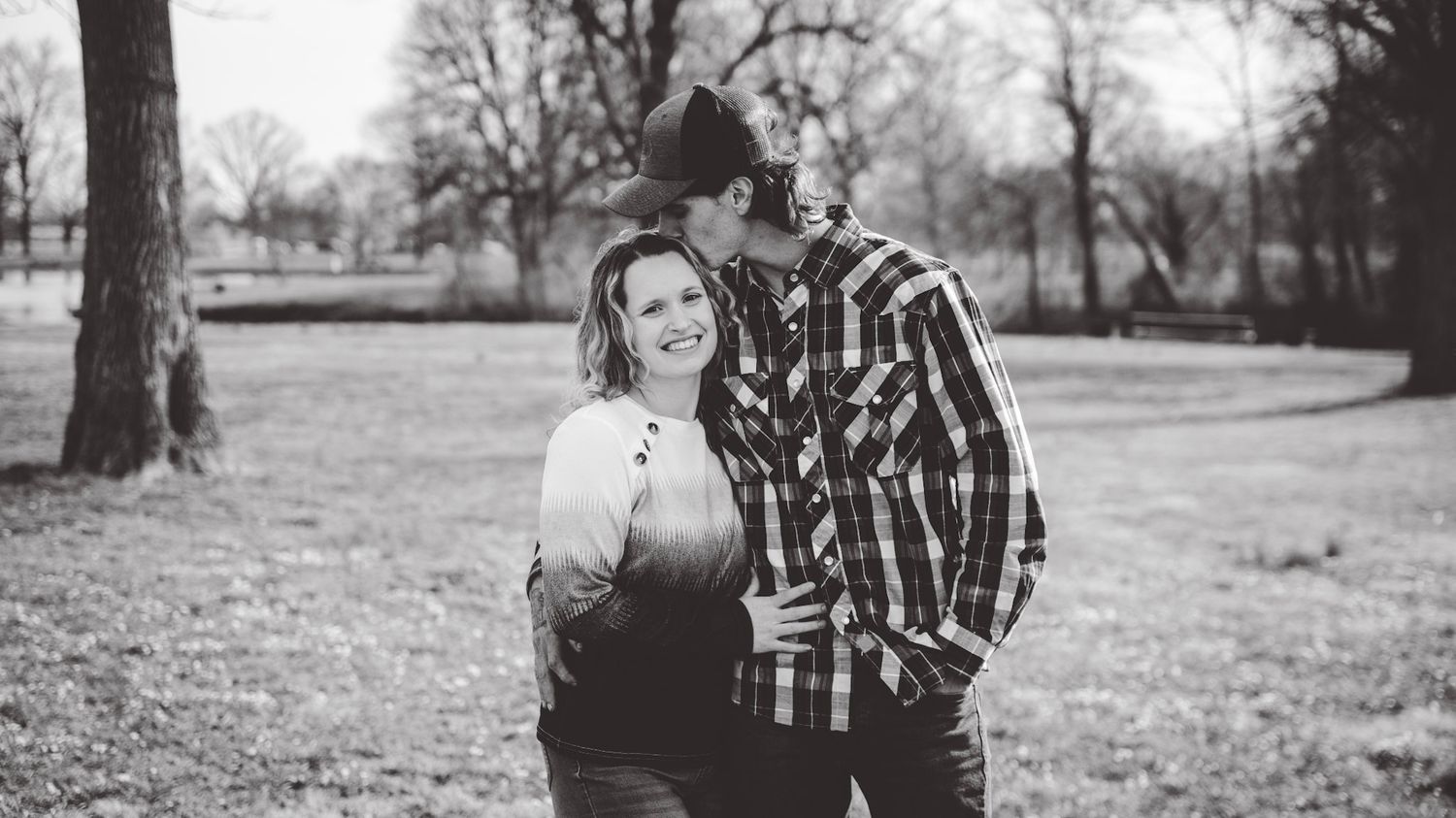 Black and white panoramic shot of a couple standing together in a park setting.