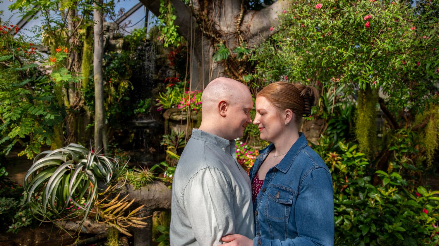 A romantic portrait of a couple in a lush garden with tropical plants.
