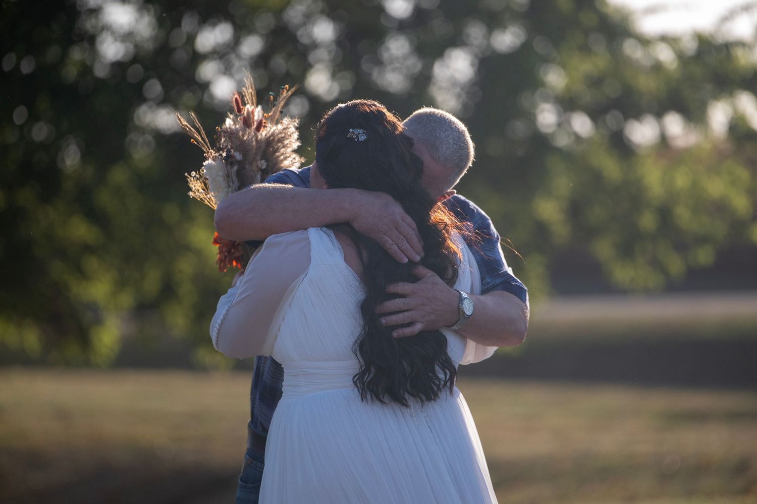 Outdoor wedding ceremony taking place under autumn trees with guests watching.