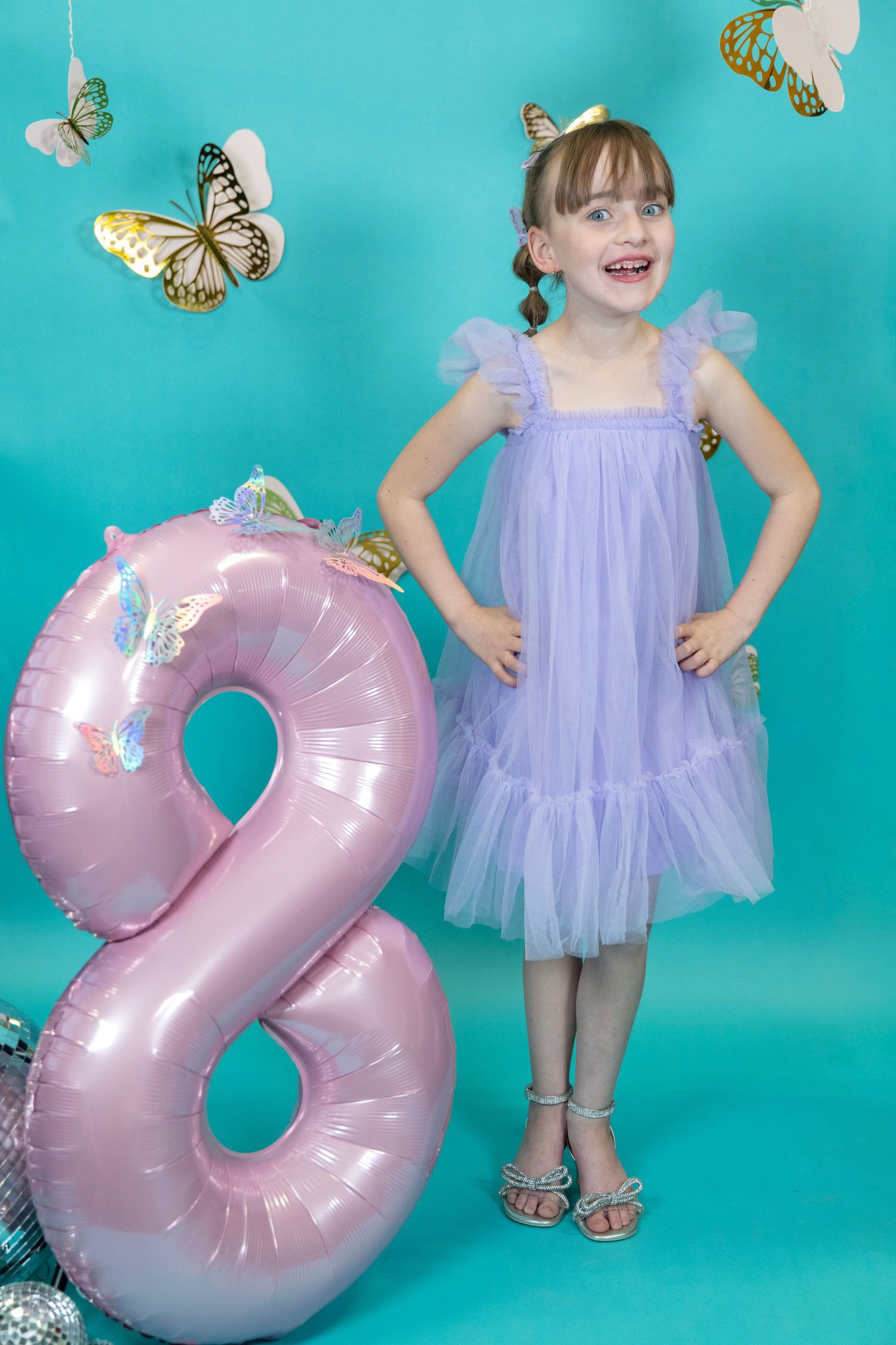 Celebratory scene with pink number 2 balloon and butterfly decorations on turquoise background.