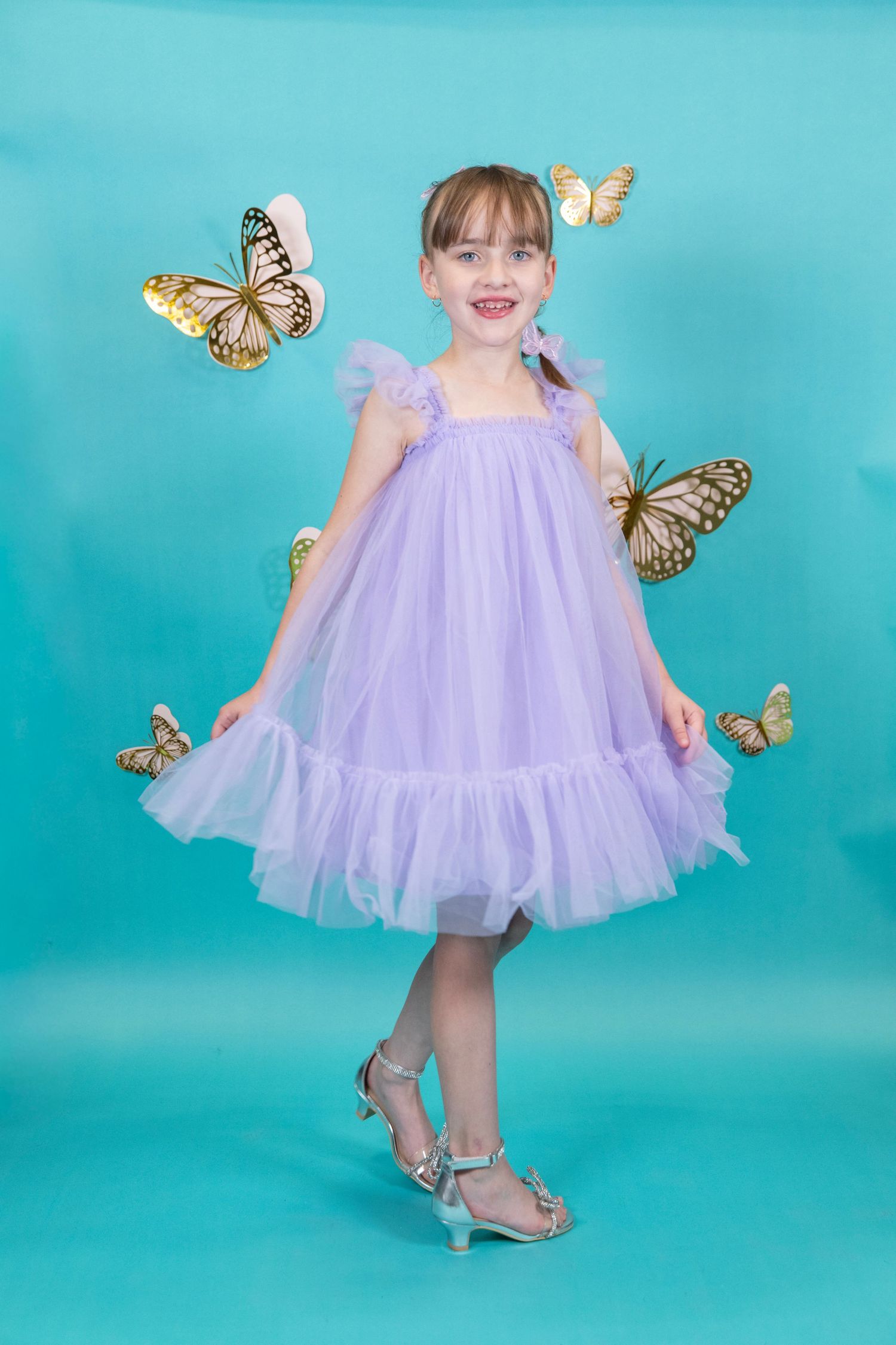Elegant pose in a lavender tulle dress with butterflies and silver sandals.