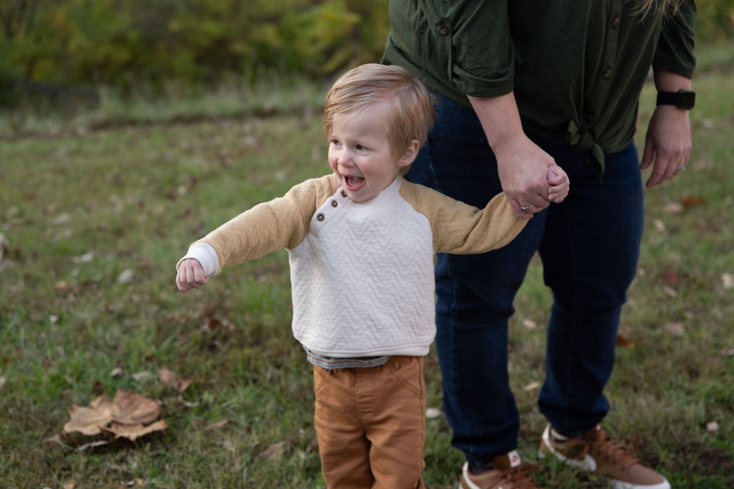 People enjoying a playful moment together in a grassy field during autumn.