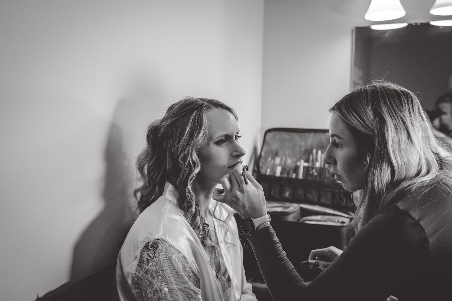 Black and white photo of wedding makeup application in progress.