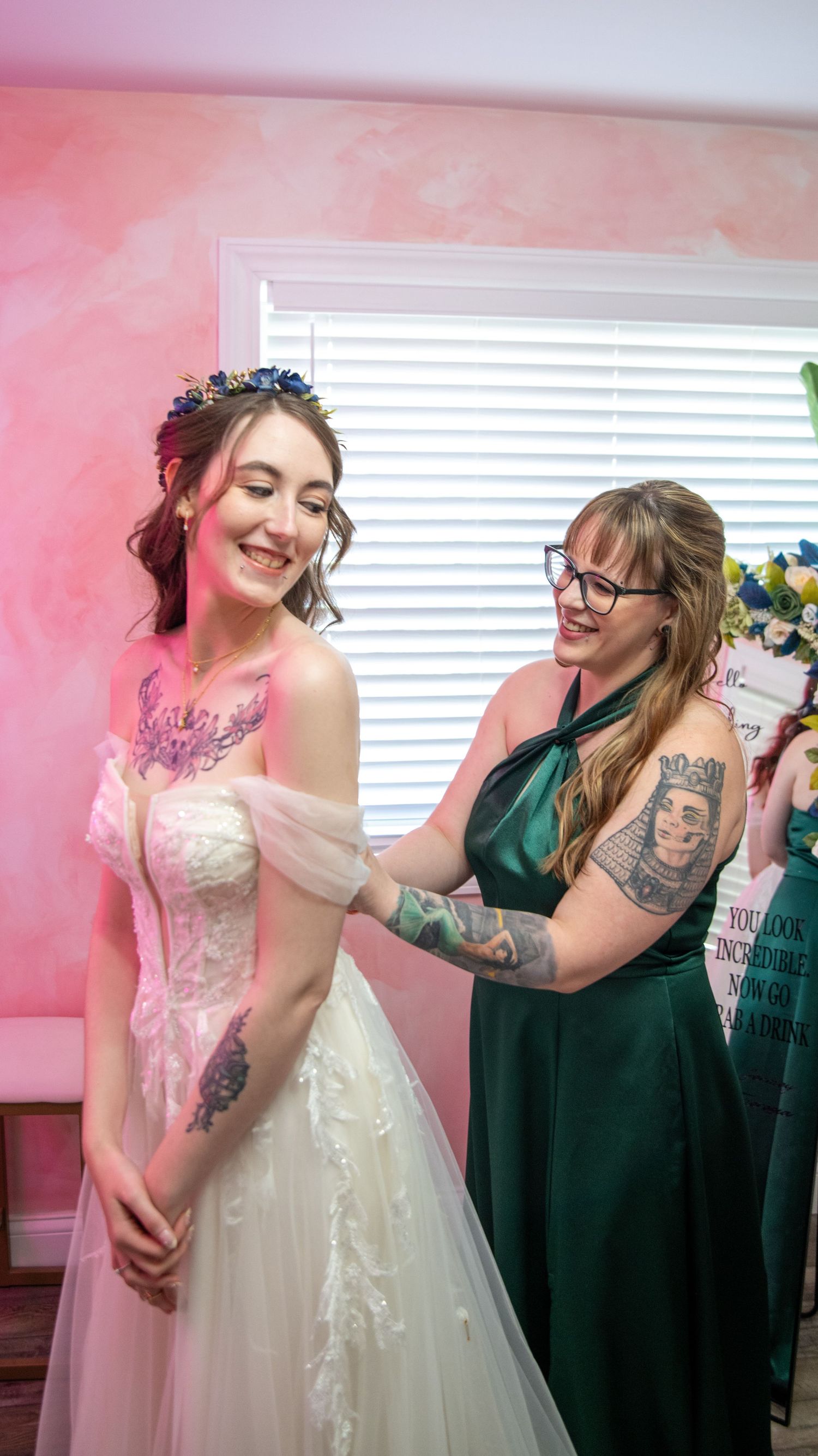 Wedding preparation scene in a pink room with joyful moments being shared.