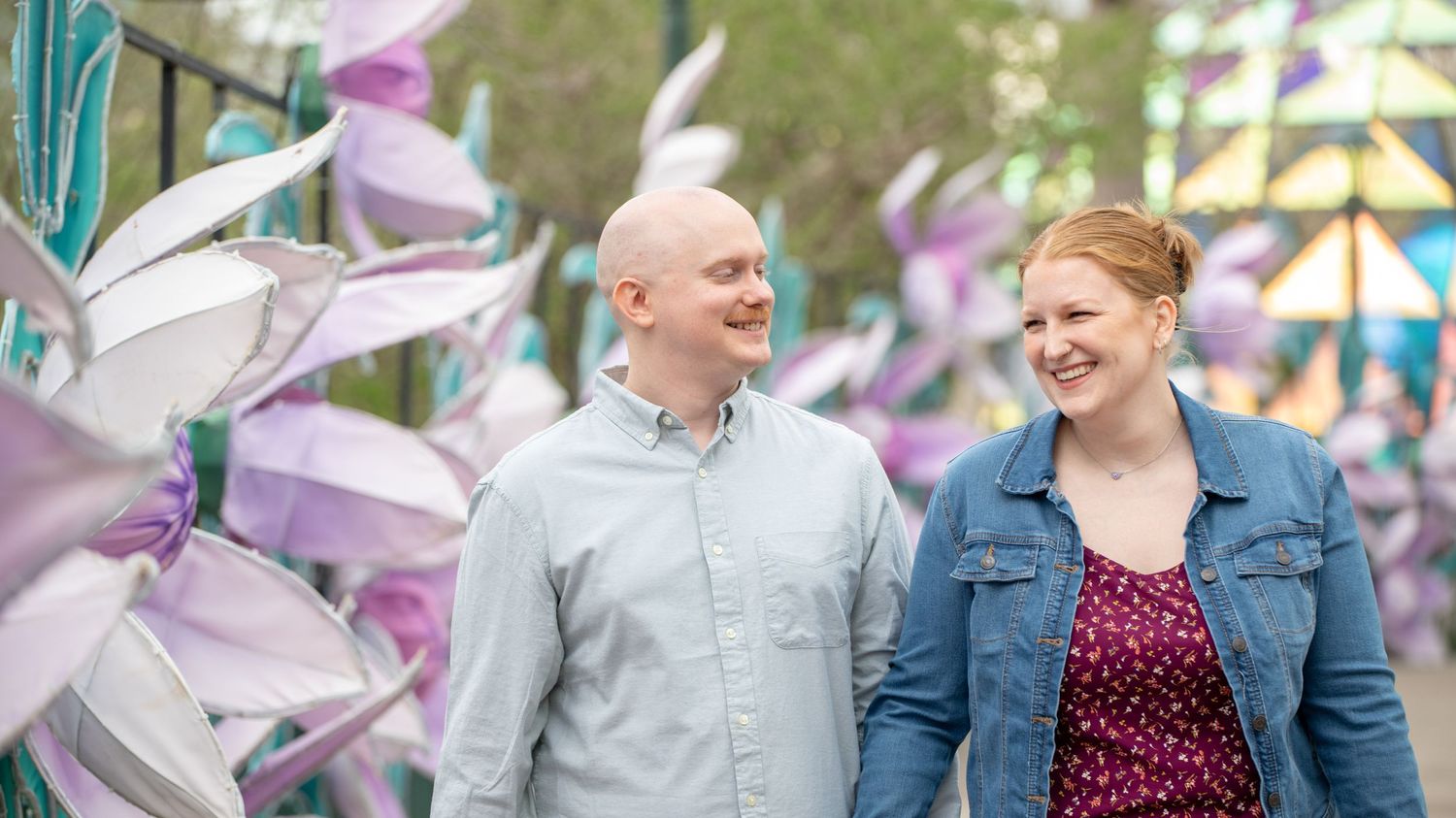 A couple shares joyful moments together outdoors with pink flowering trees in the background.