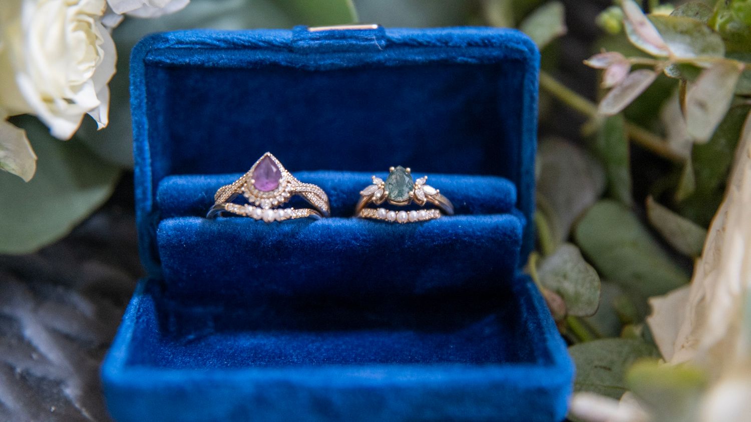 Two elegant diamond rings nestled in a royal blue velvet ring box.
