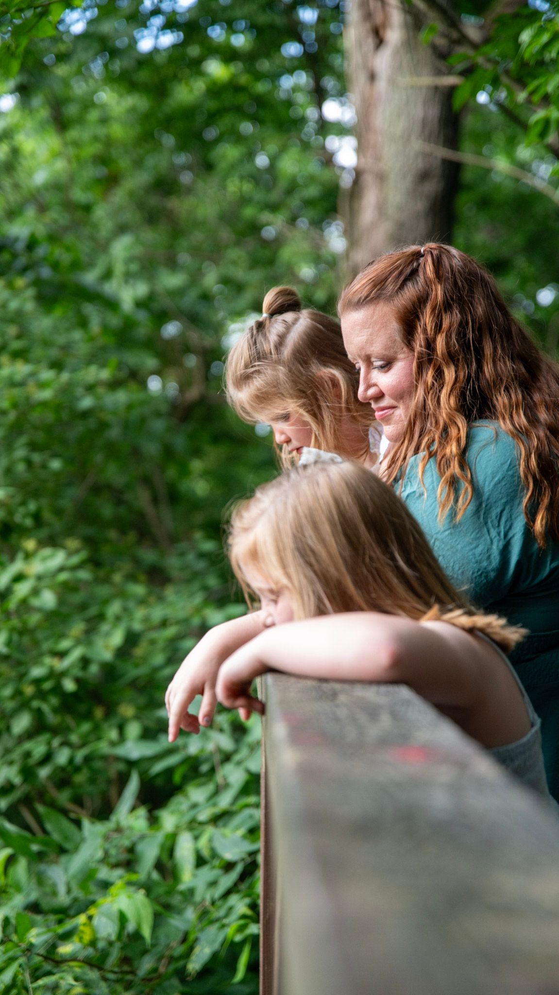 Intimate moments shared on a wooded path surrounded by lush green foliage.