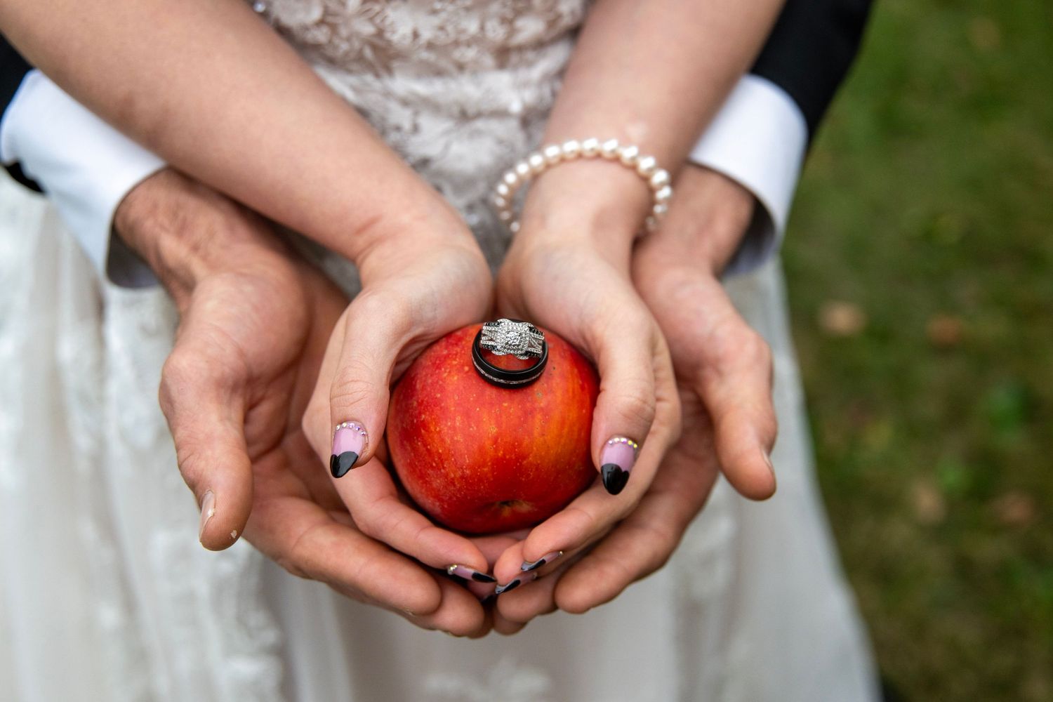 Close-up shots of hands holding a bright red apple against formal wedding attire.