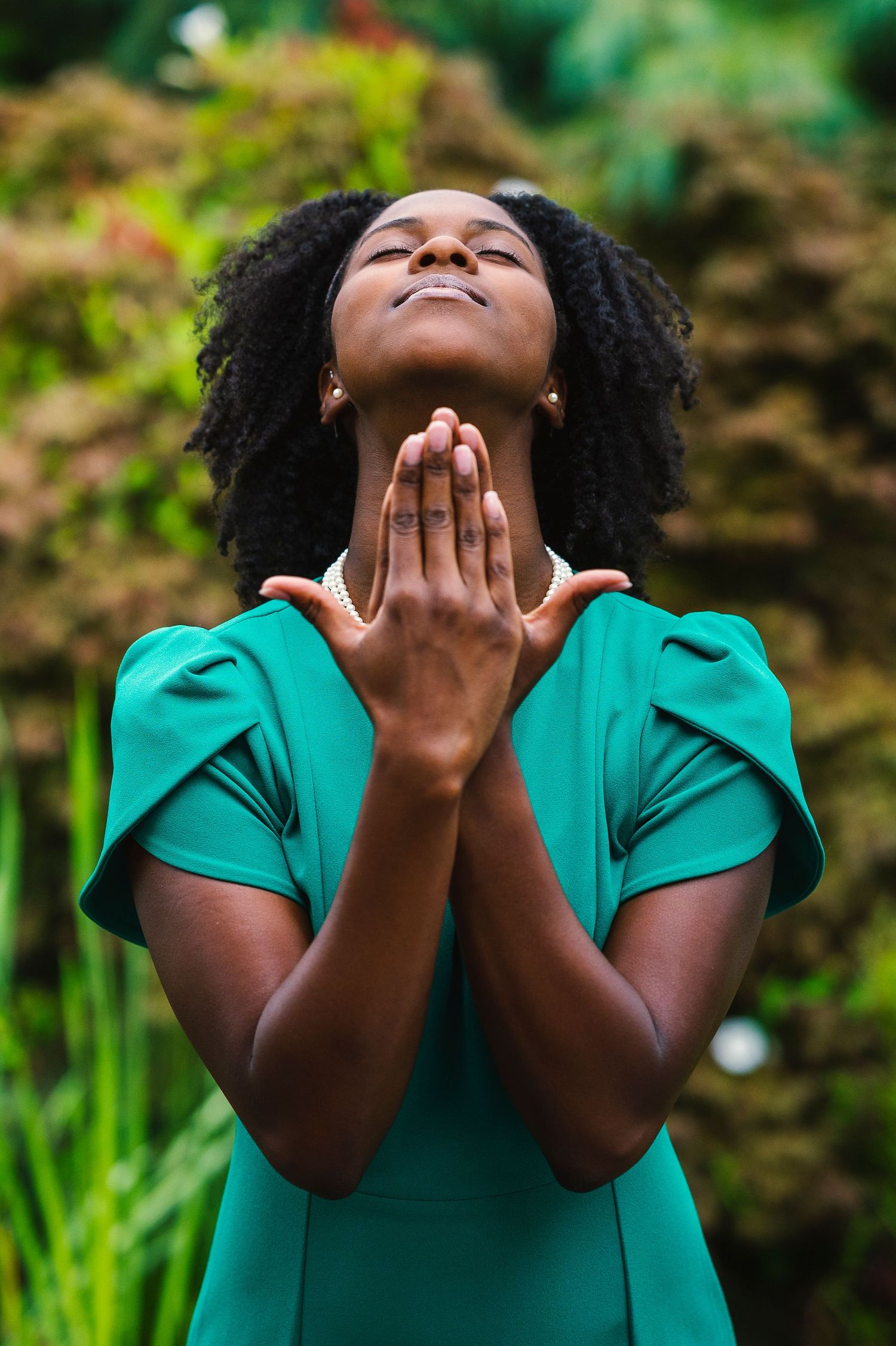 Woman in emerald green dress expressing joy outdoors with natural lighting.