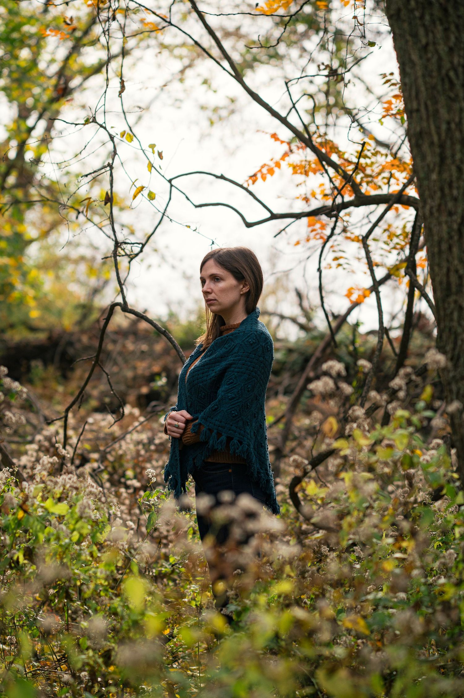 Artistic autumn portrait through tree branches with soft natural lighting.