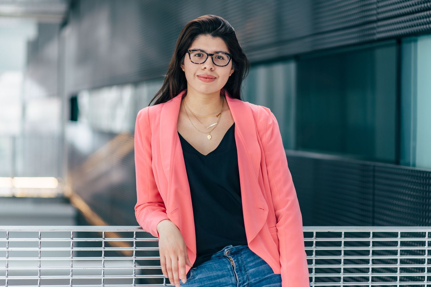 Professional portrait series in coral blazer against modern office background.