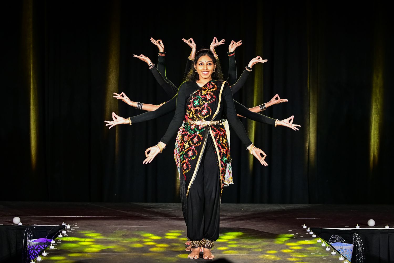 Dramatic stage performance with dancers in black costumes under spotlights.