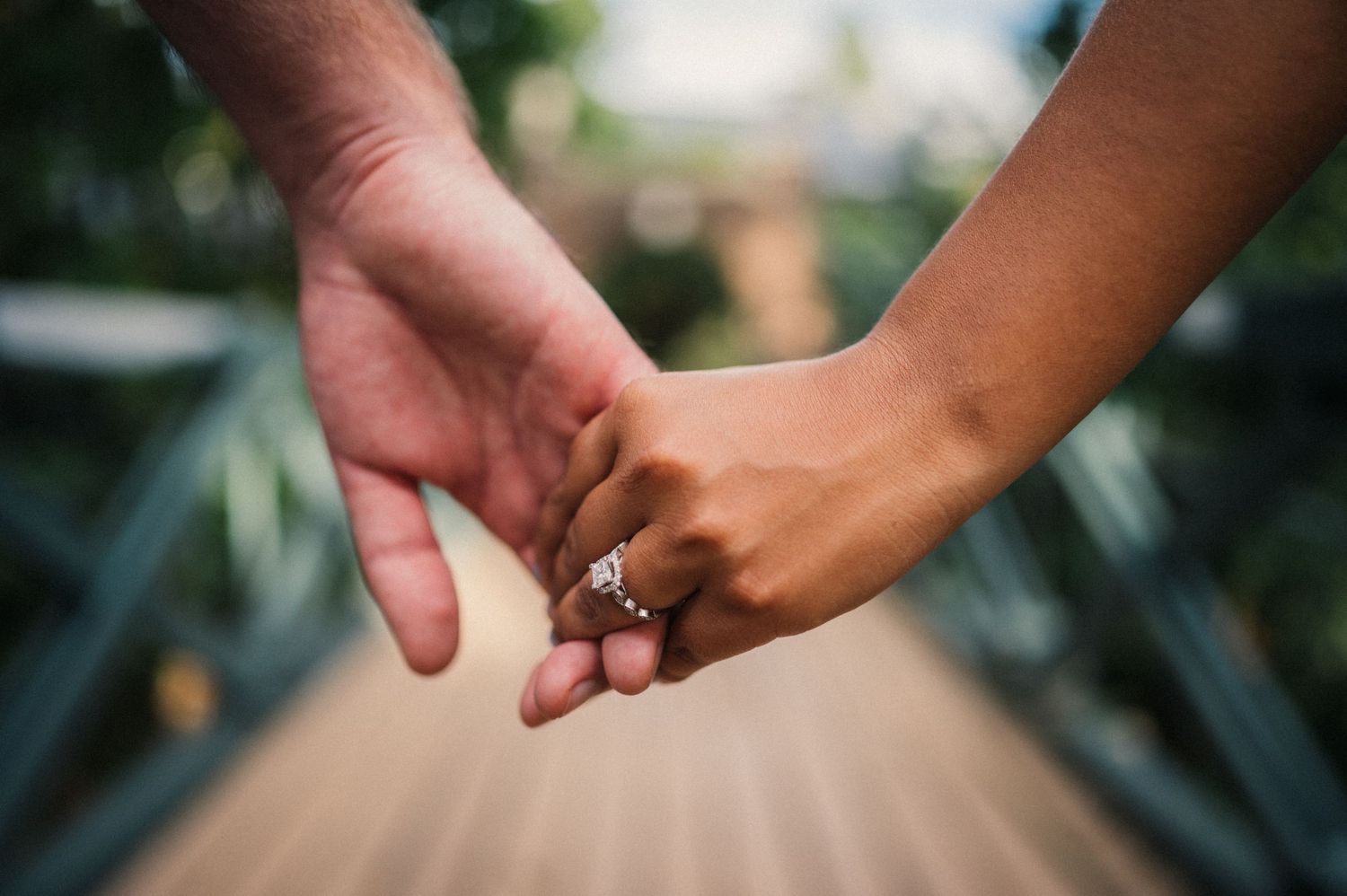 Close-up of hands reaching toward each other showing engagement or wedding rings.