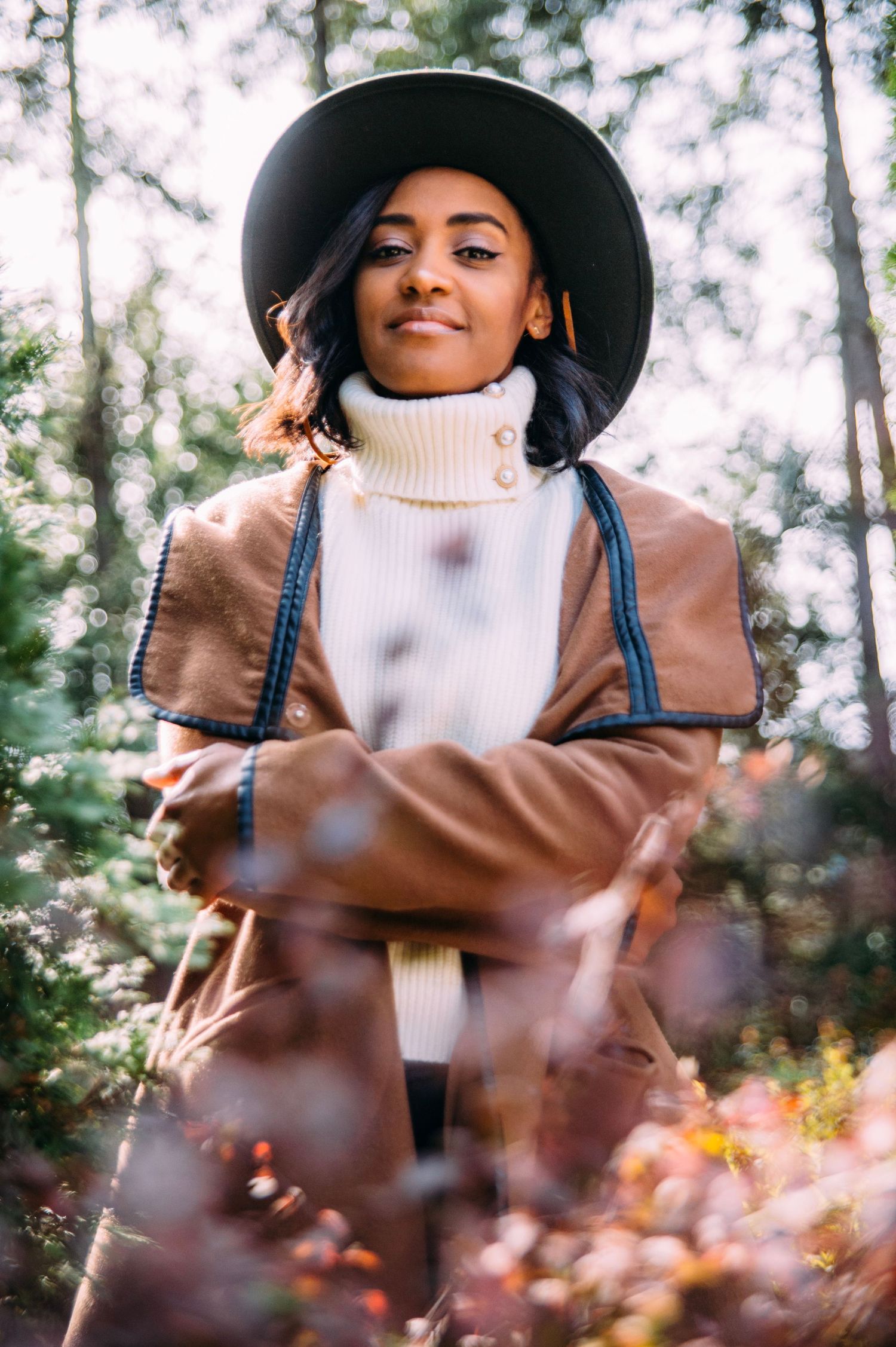 Fashion portrait series featuring a wide-brimmed hat and cream turtleneck sweater among autumn foliage.