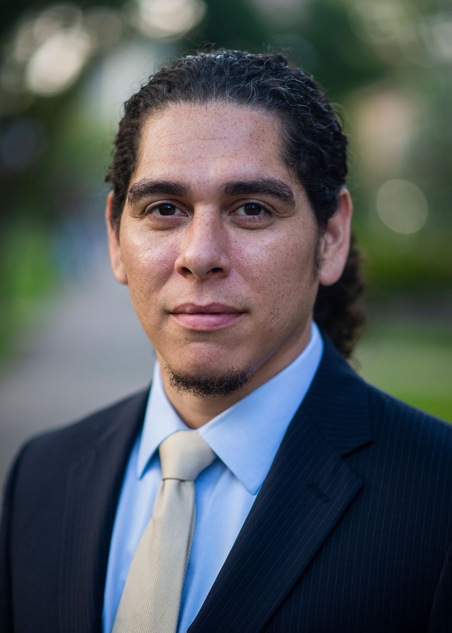 Professional headshots in dark suit and tie against blurred background.
