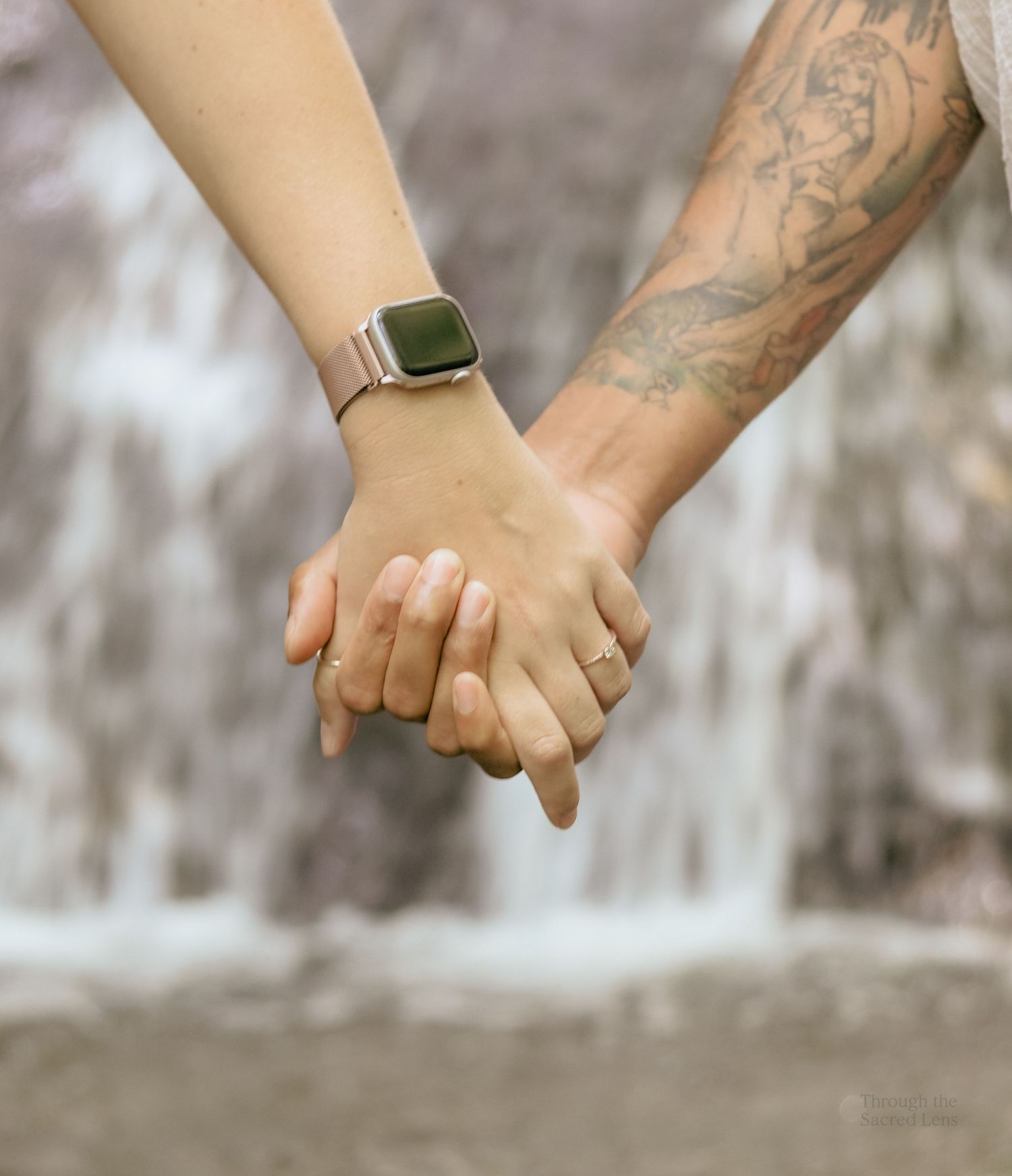 Close-up sequence of hands holding each other against a waterfall backdrop.