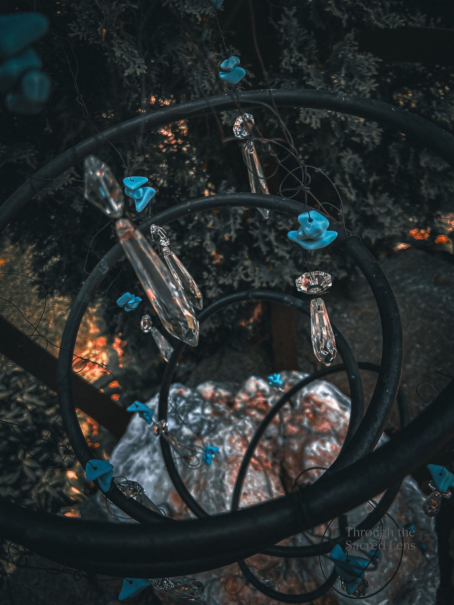 Glowing blue crystals and metallic objects arranged around a dark circular frame with embers burning in the background.