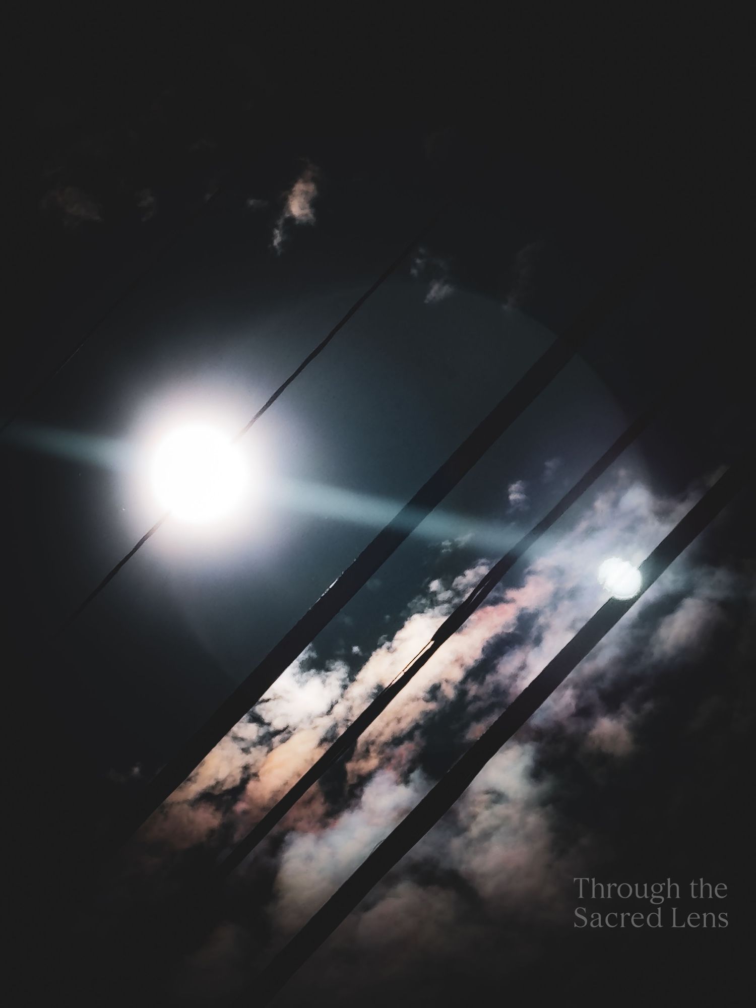 Dramatic night sky with moonlight breaking through dark clouds and power lines.