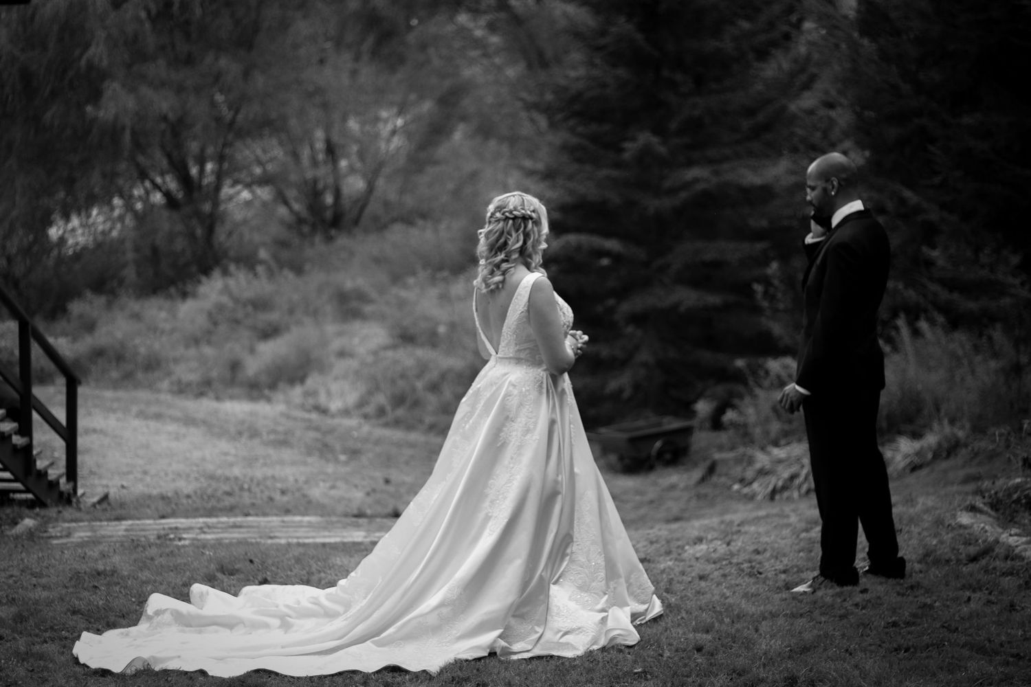 Outdoor wedding ceremony with long train dress against natural backdrop.