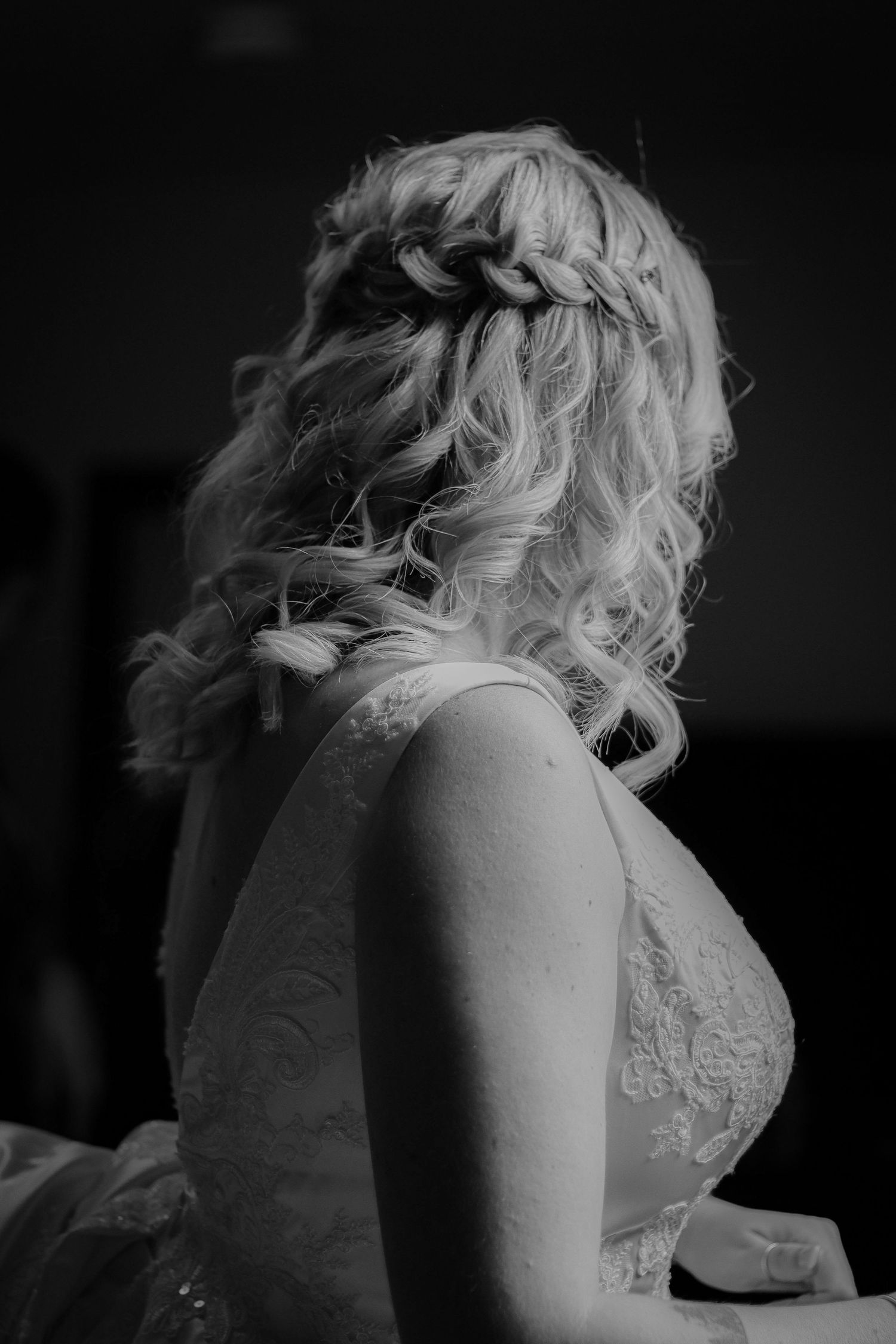 Black and white portrait showing elegant curled hairstyle with braided detail and lace dress detail.
