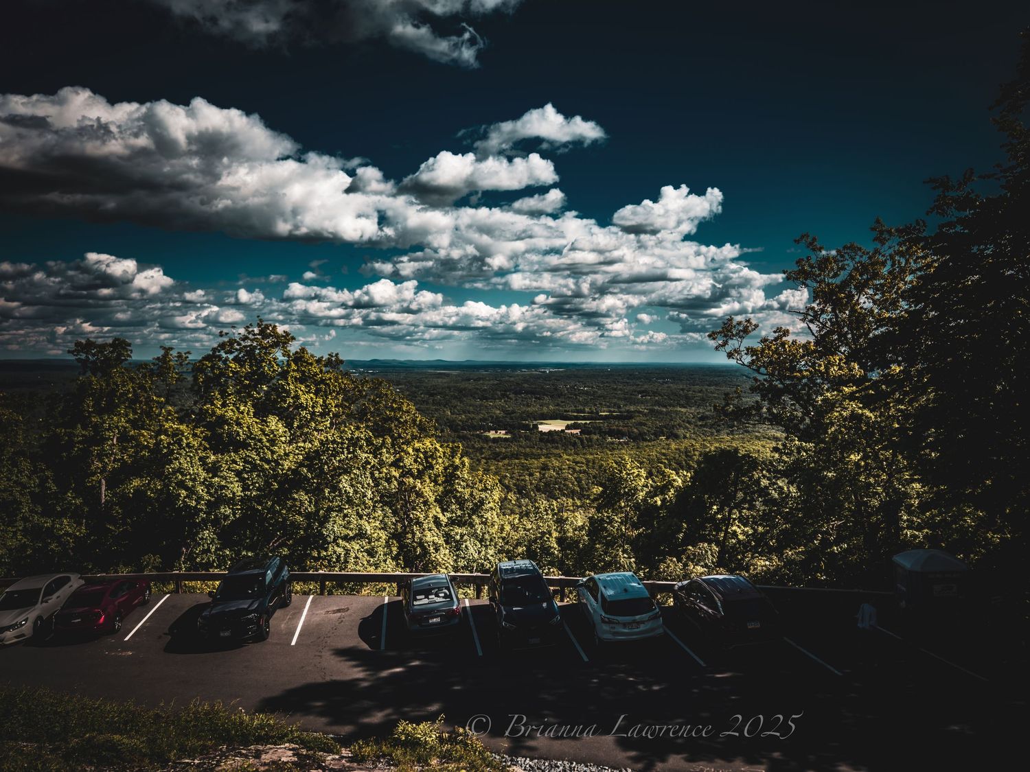 Dramatic landscape with rolling hills and scattered clouds under deep blue sky.