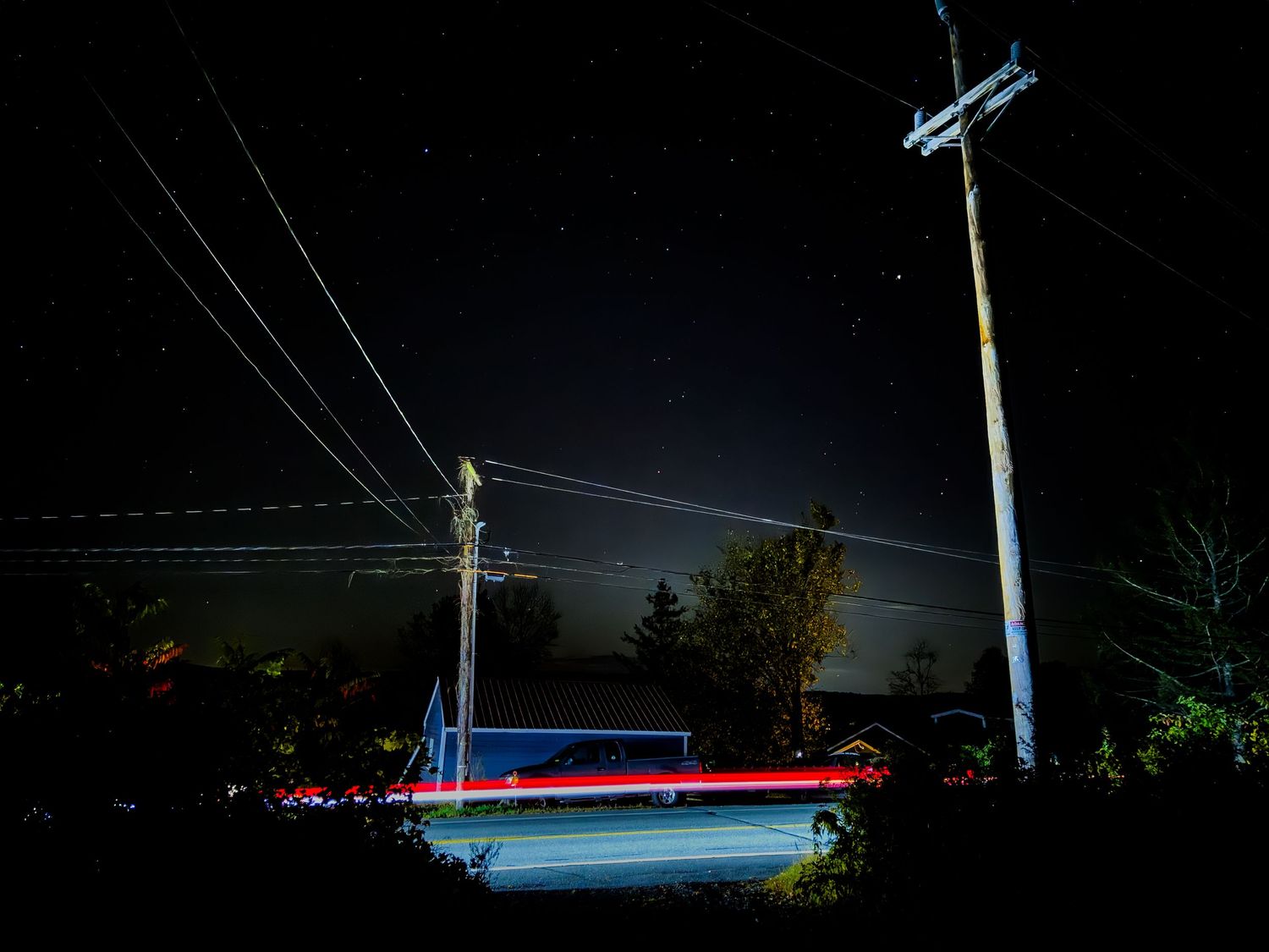 Power lines and utility poles silhouetted against a dark night sky.