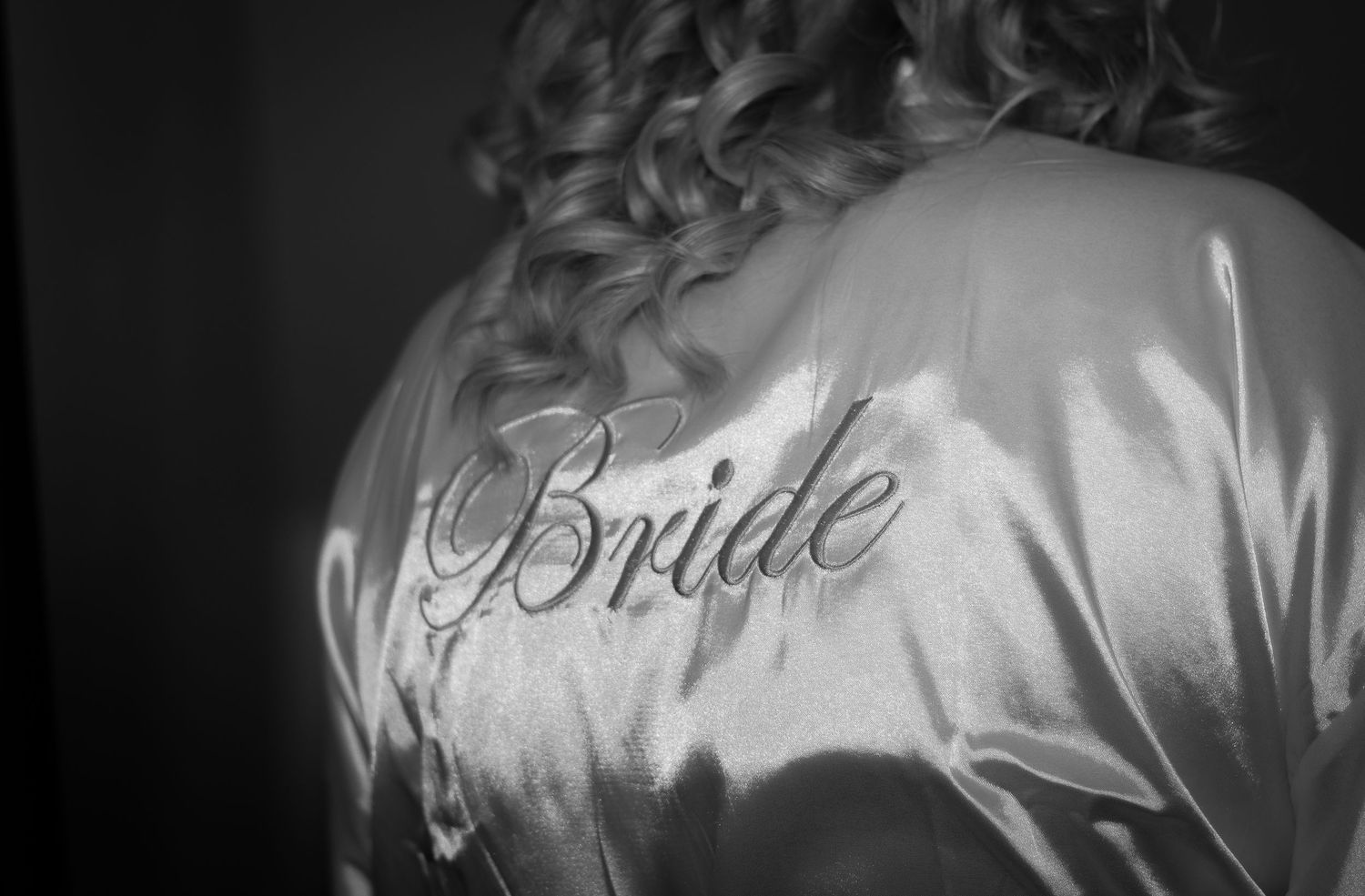 Close-up of bride's satin robe with text embroidered on the back.