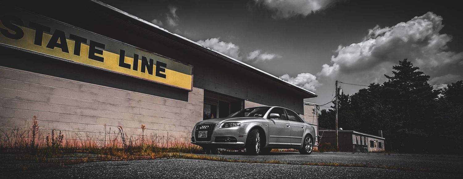 A dramatic black and white landscape with Luxury Audi and dramatic cloudy sky in the background.