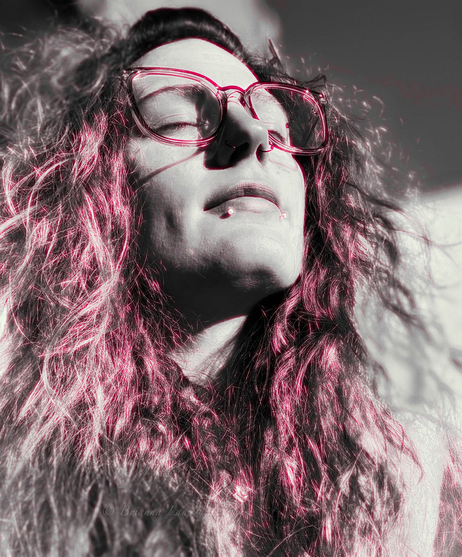 Artistic portrait with pink-tinted hair and glasses in black and white contrast.