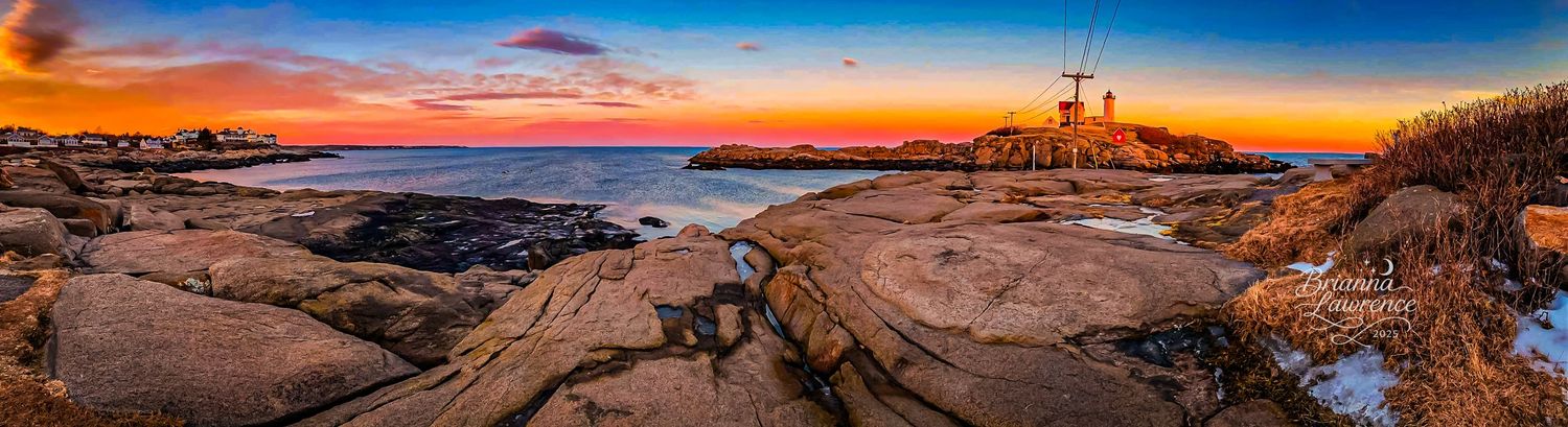 Dramatic sunset over rocky coastal lighthouse with vibrant orange sky reflecting on granite cliffs.