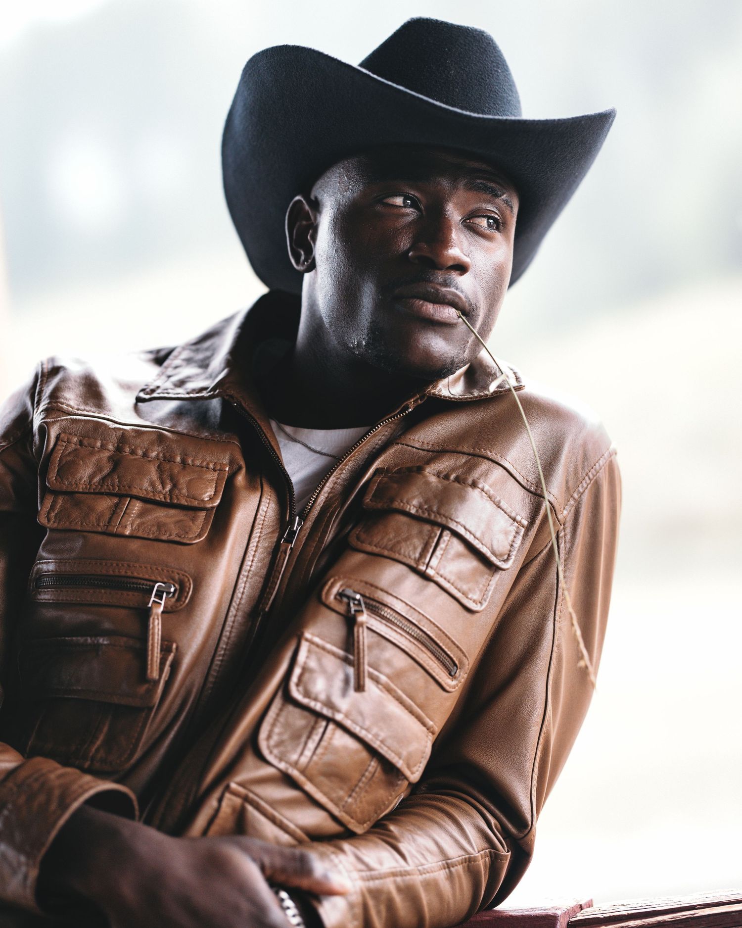 Man in a cowboy hat and brown leather jacket seated for a portrait at a workshop in Canmore.