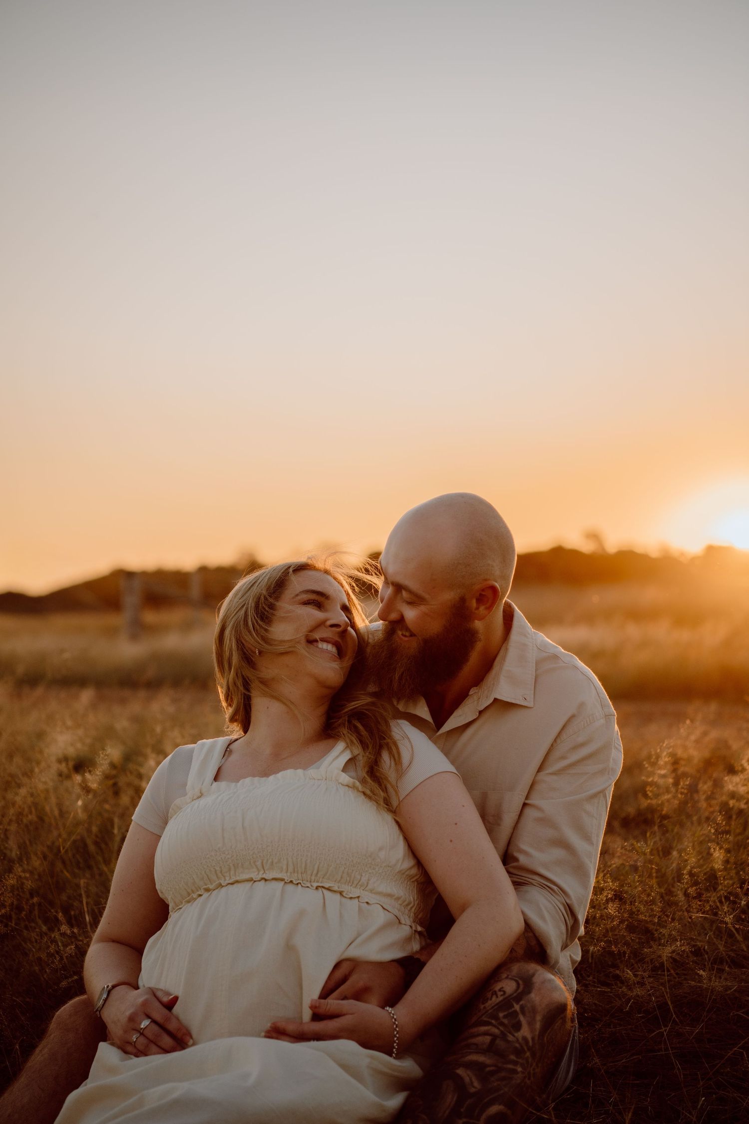 A romantic sunset photoshoot in a rural field with golden light.