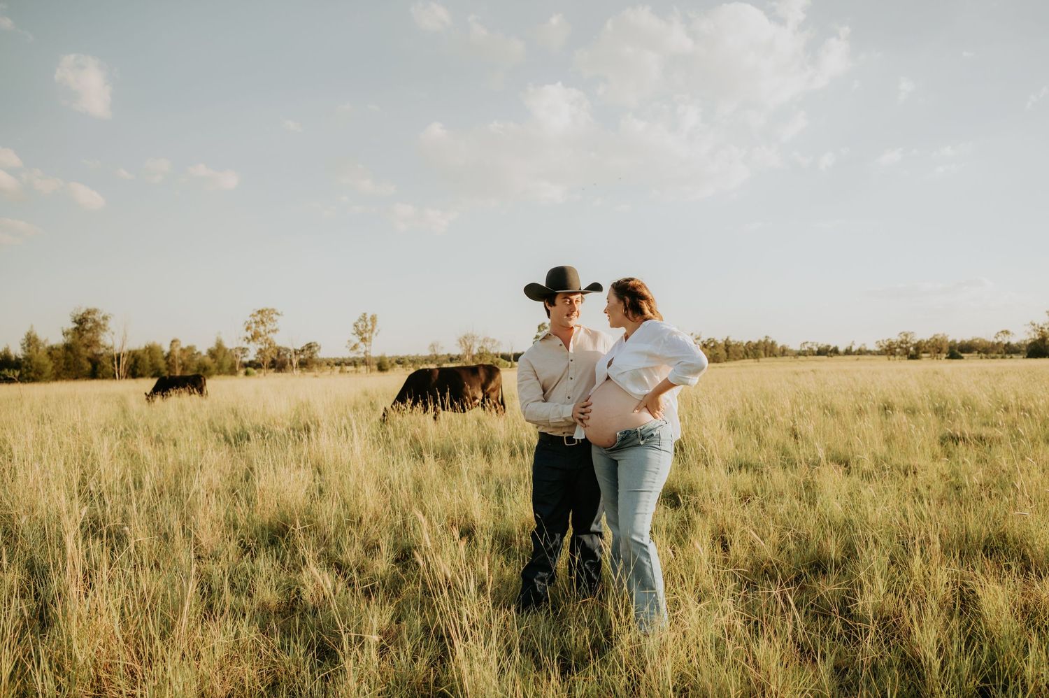 People walking together across a vast grassy plain with cattle grazing in the distance.