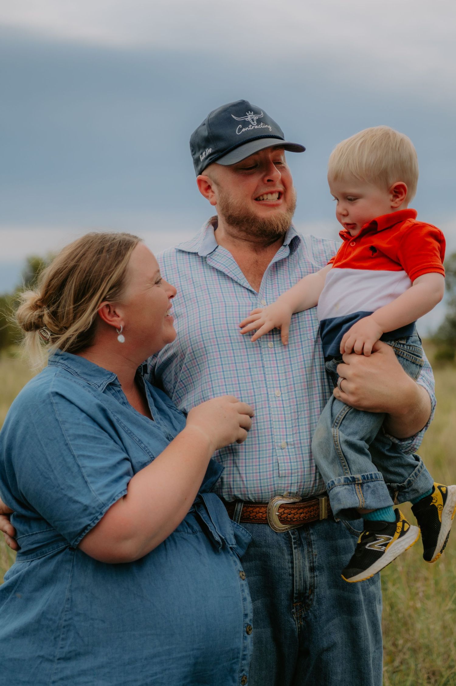 A family shares joyful moments together in a field during an outdoor photo session at sunset.