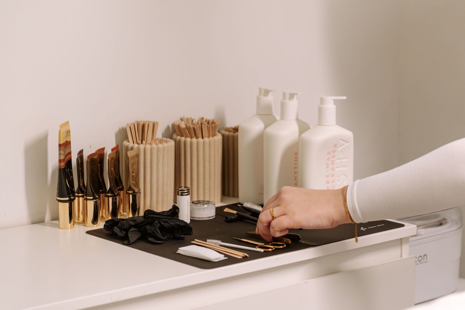 Organized beauty salon counter with makeup brushes, wooden sticks, and white bottles.