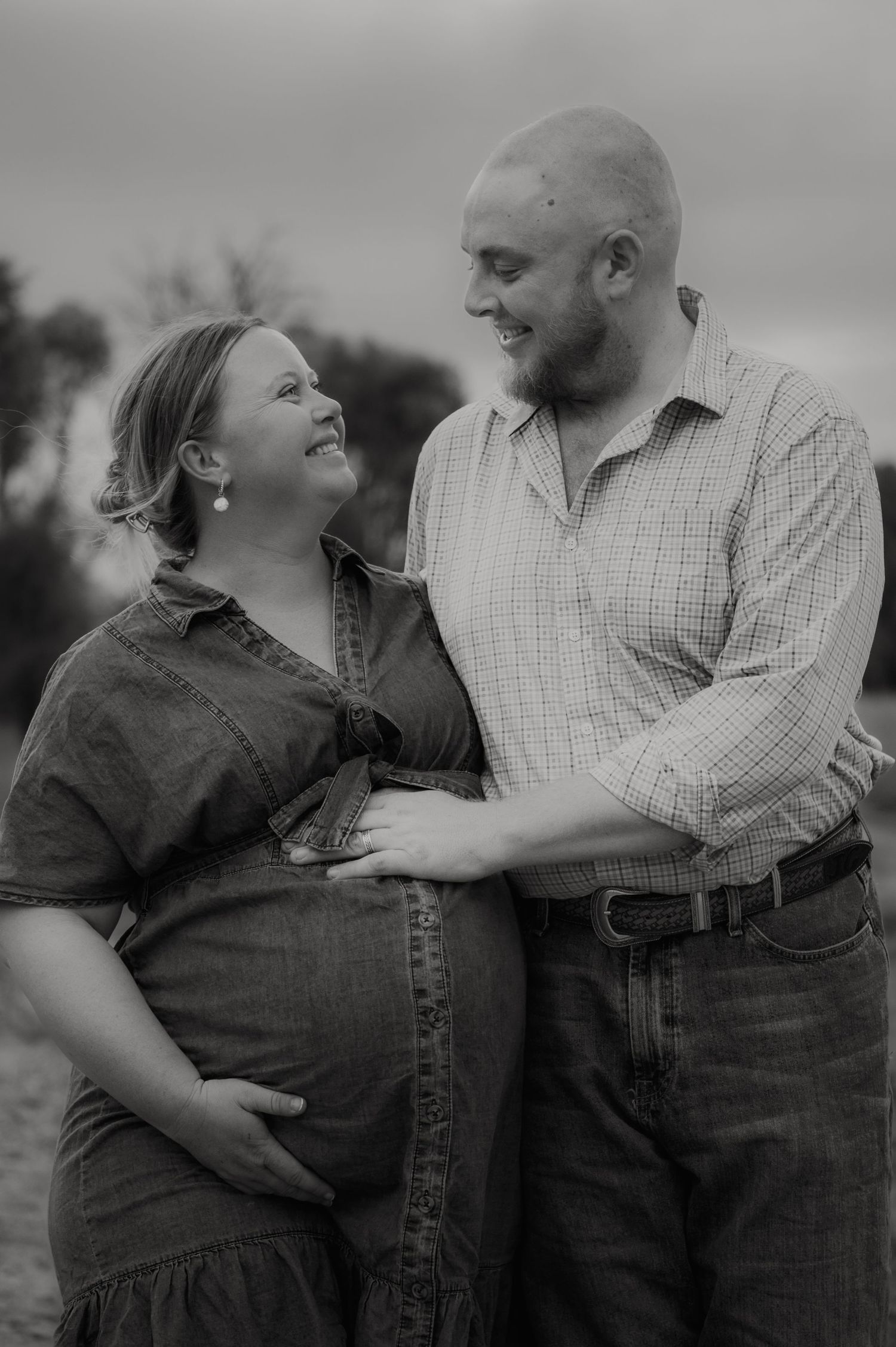 A romantic black and white photo series showing a couple laughing and embracing outdoors in casual attire.