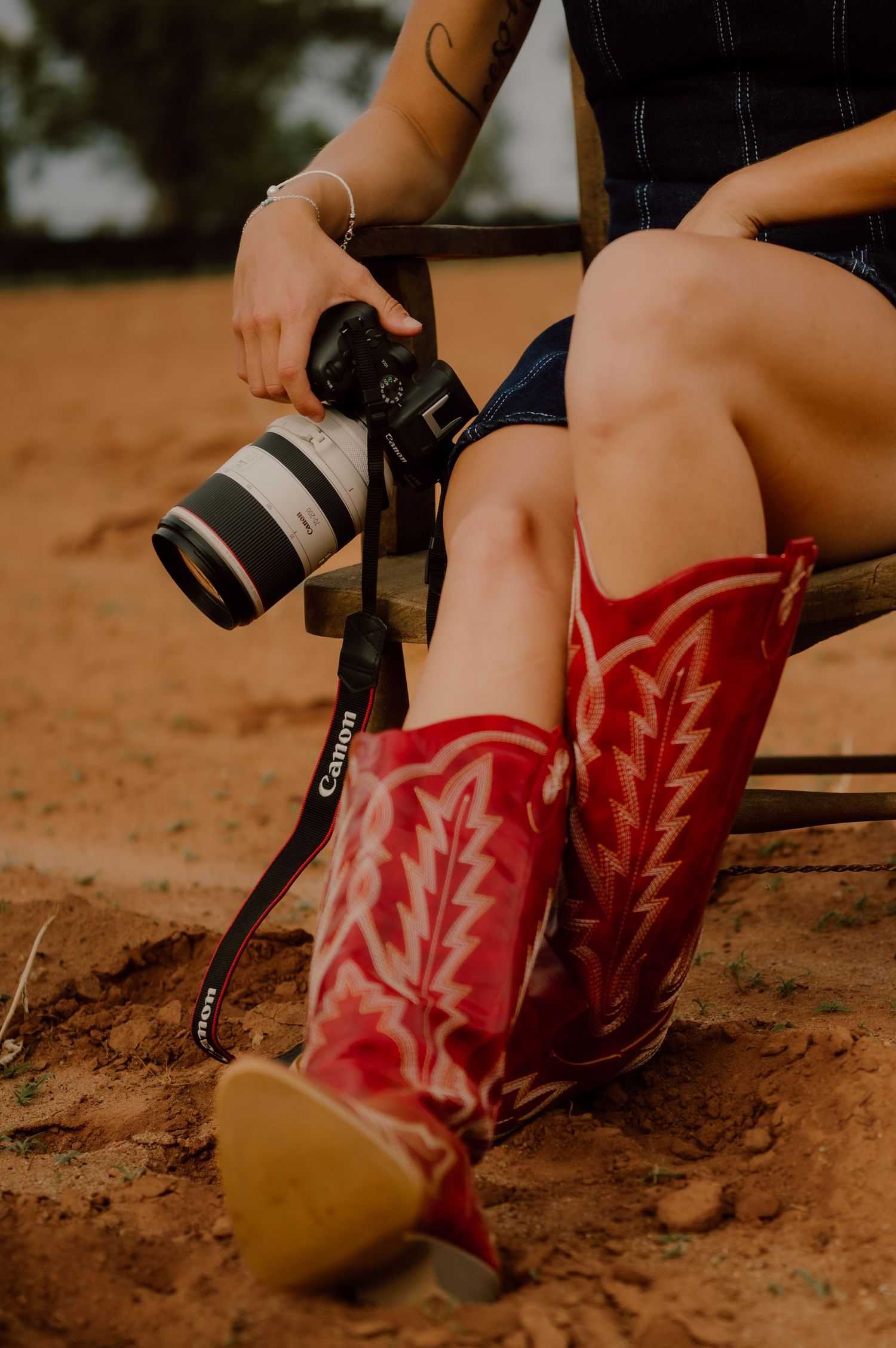 Red leather cowboy boots with floral embroidery stand out against dusty ground in a series of artistic shots.