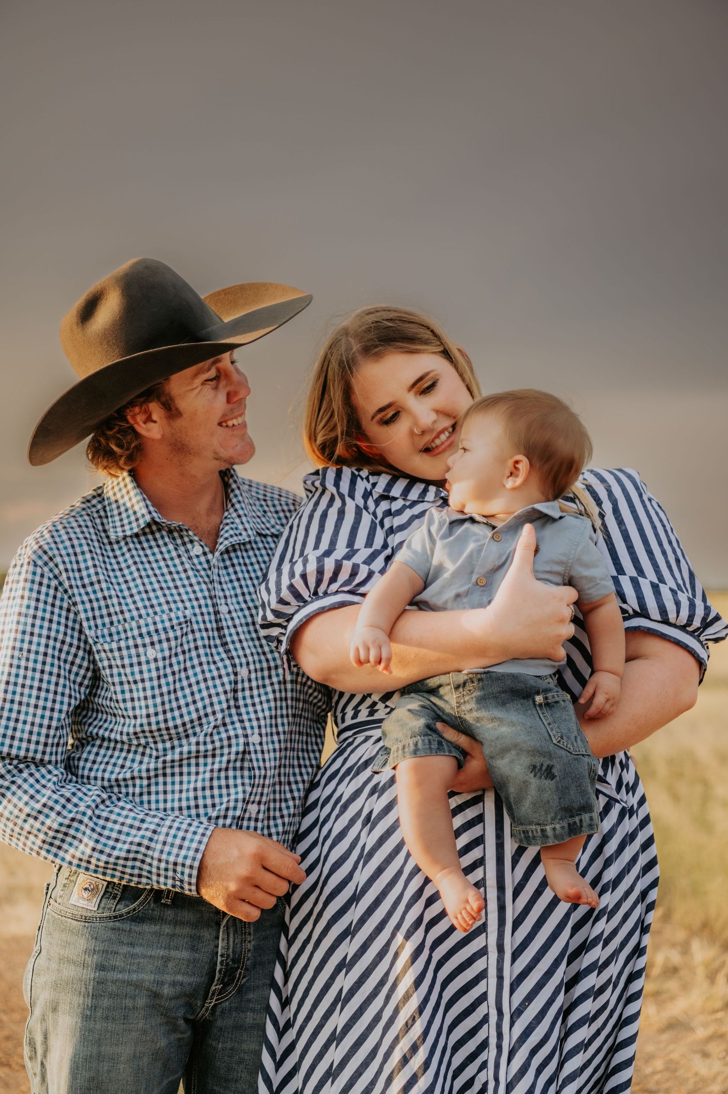 A family in western wear shares tender moments together in a series of casual outdoor portraits.