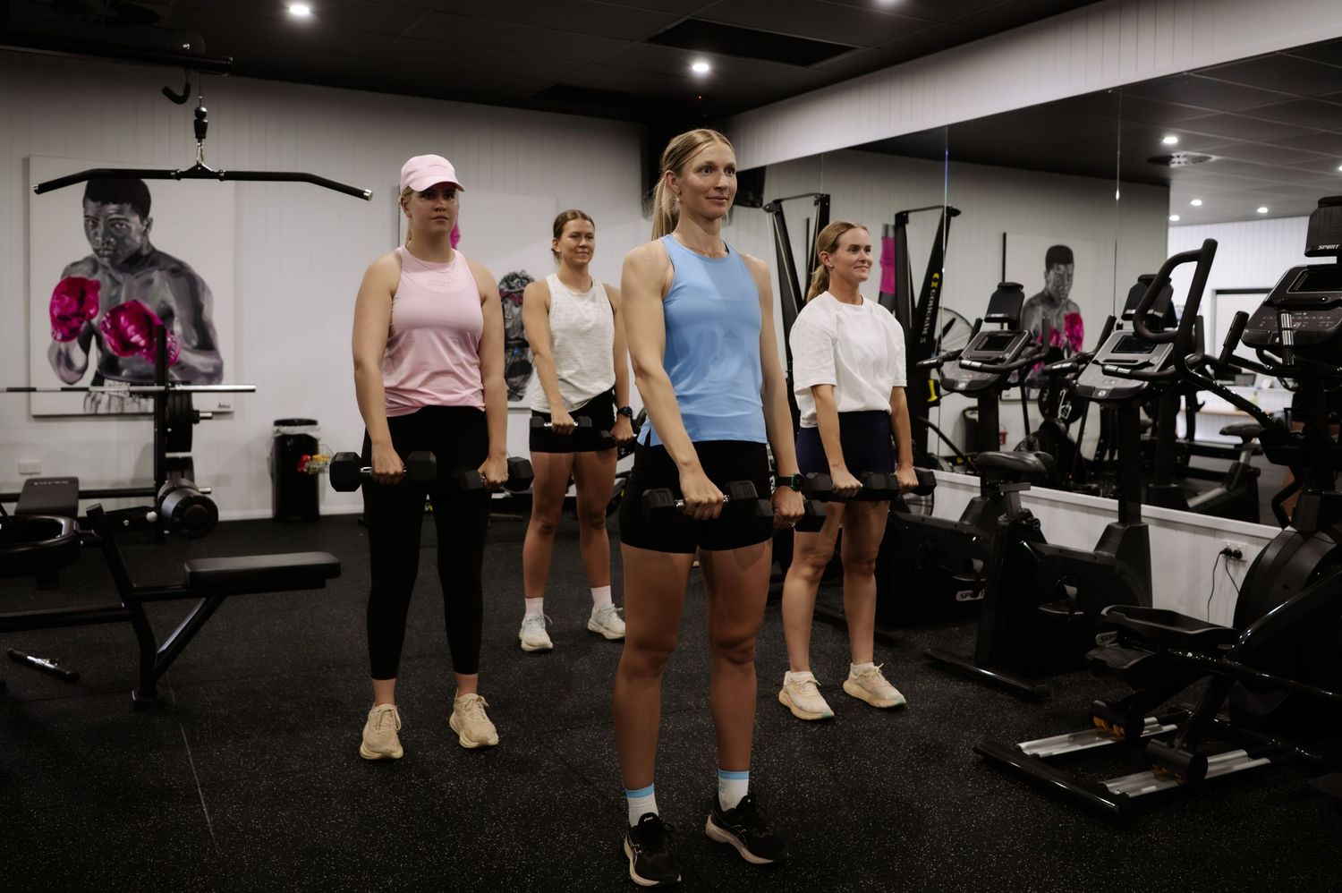 People working out in a modern fitness gym with exercise equipment and weights.